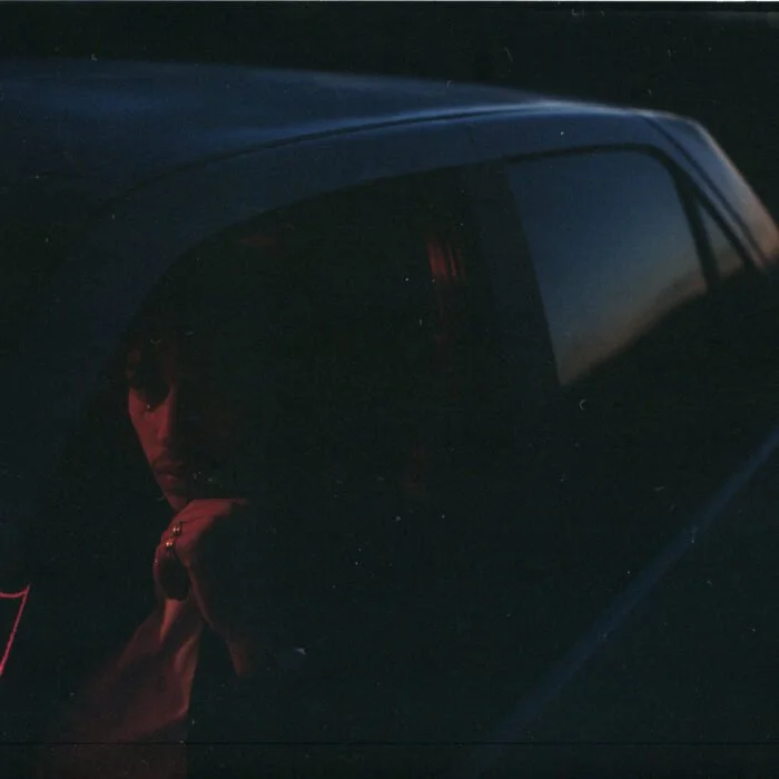 Une personne regarde par une vitre teintée dans une voiture dans l'obscurité.