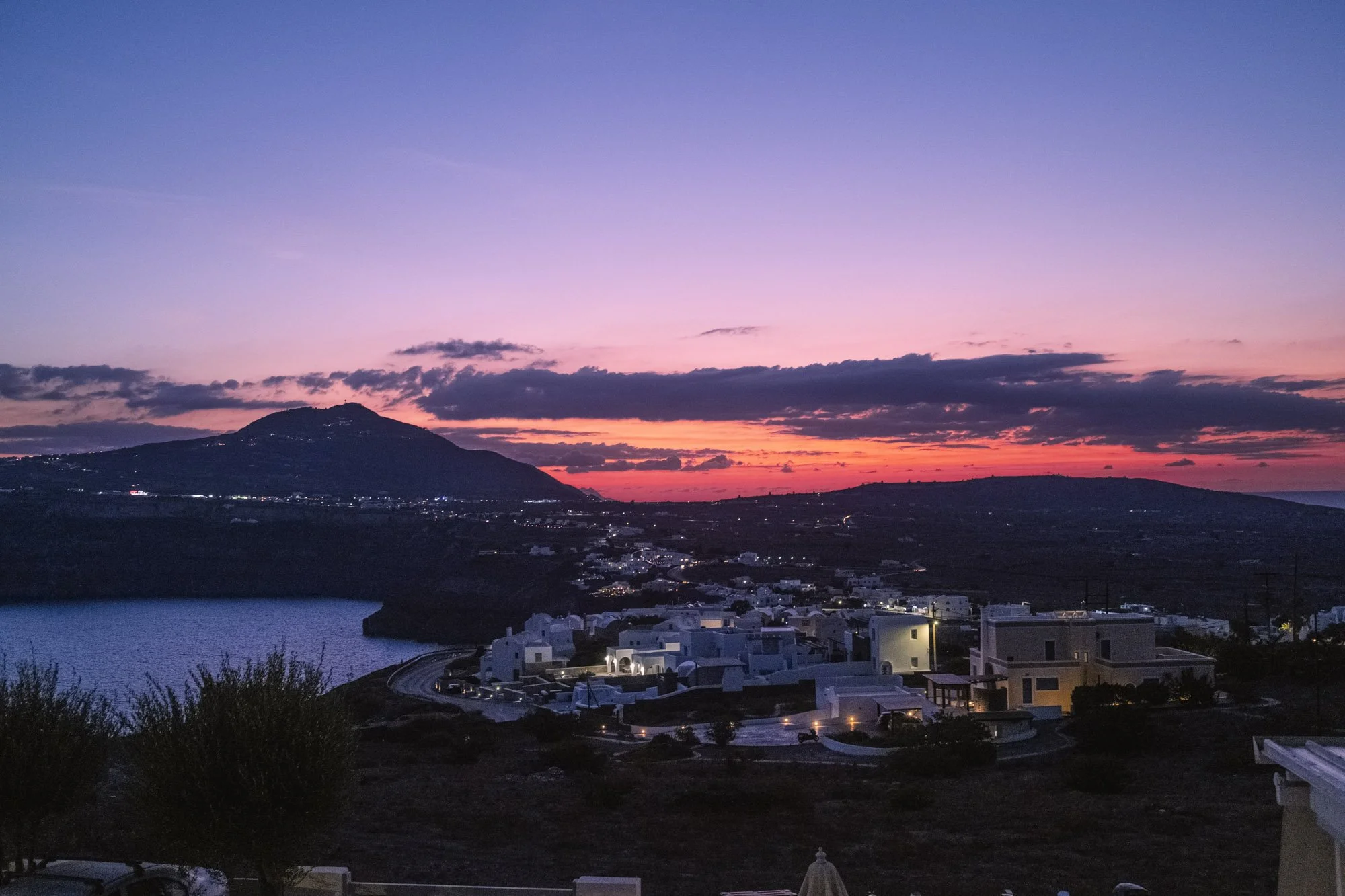 Coucher de soleil sur un paysage insulaire avec une mer, des collines et un village de maisons blanches énergisantes à santorin