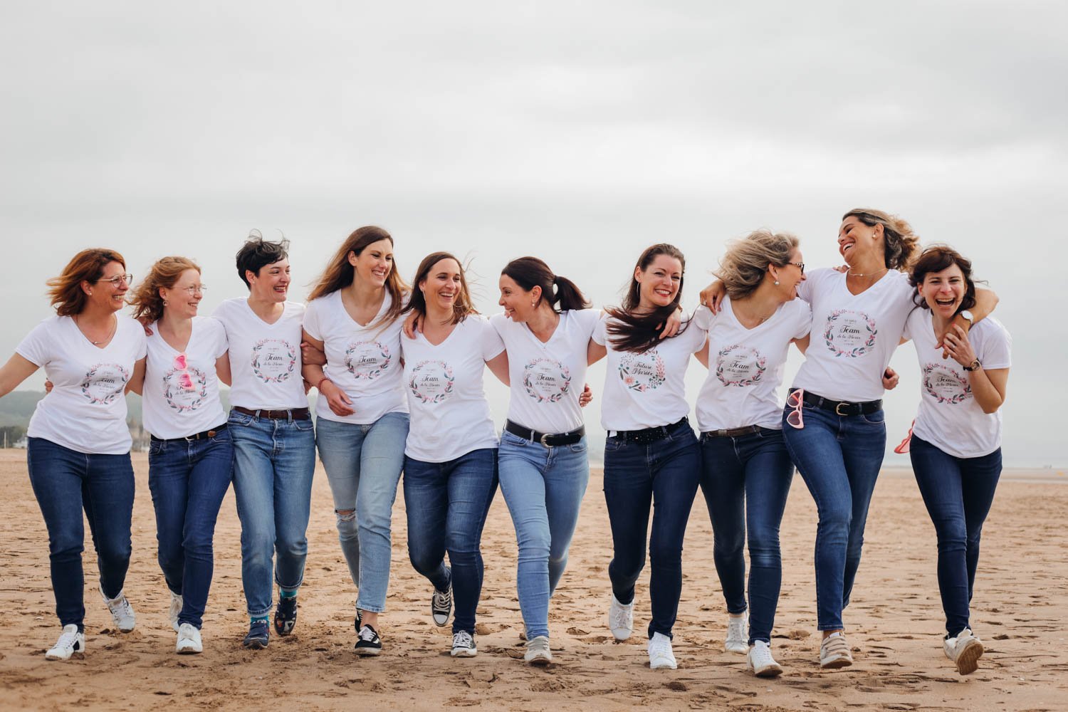 Groupe de femmes marchant ensemble sur la plage, souriant et partageant un moment convivial.