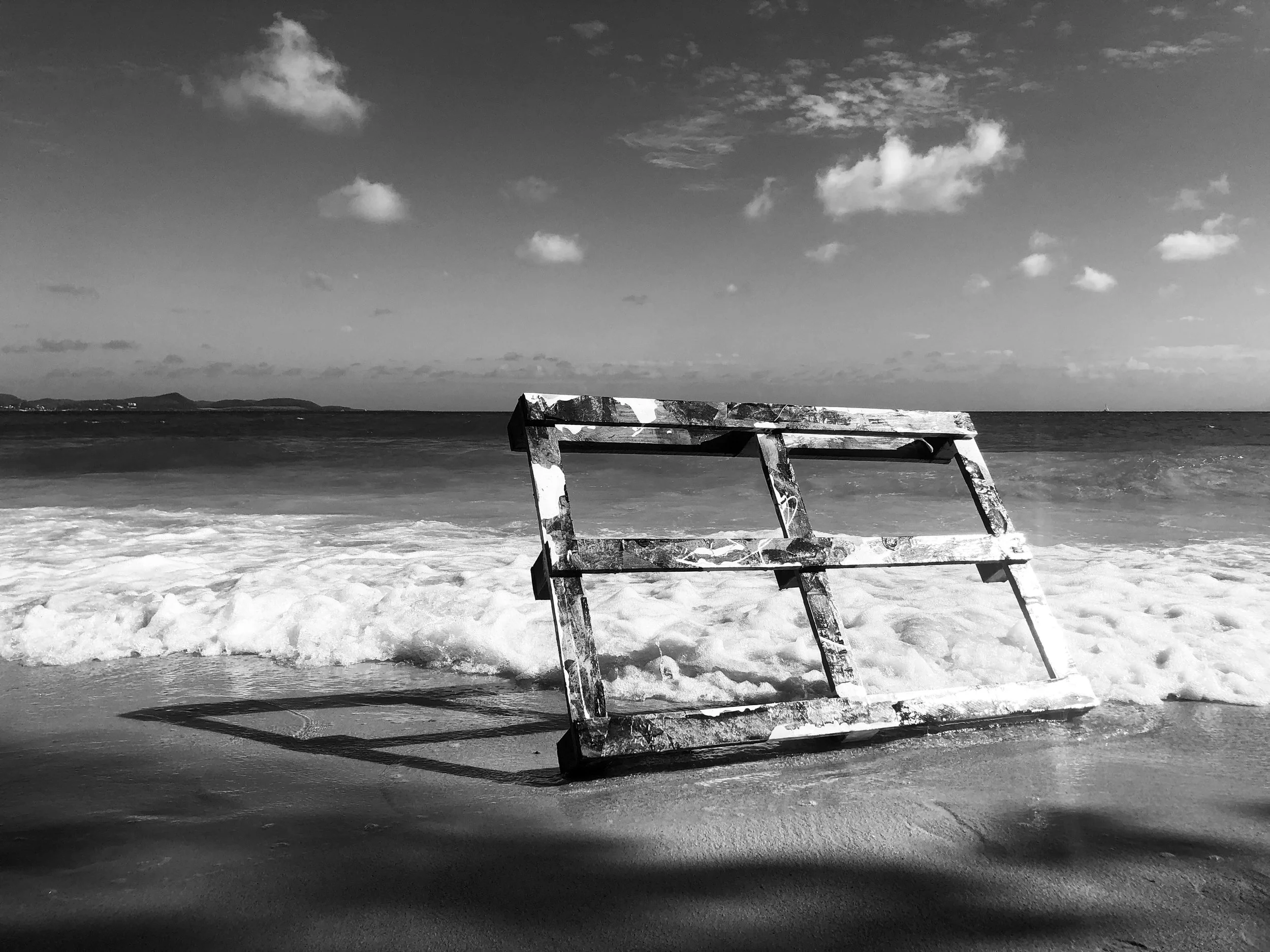 Une chaise de plage abandonnée sur une plage au bord de l'océan, avec un ciel nuageux en arrière-plan.
