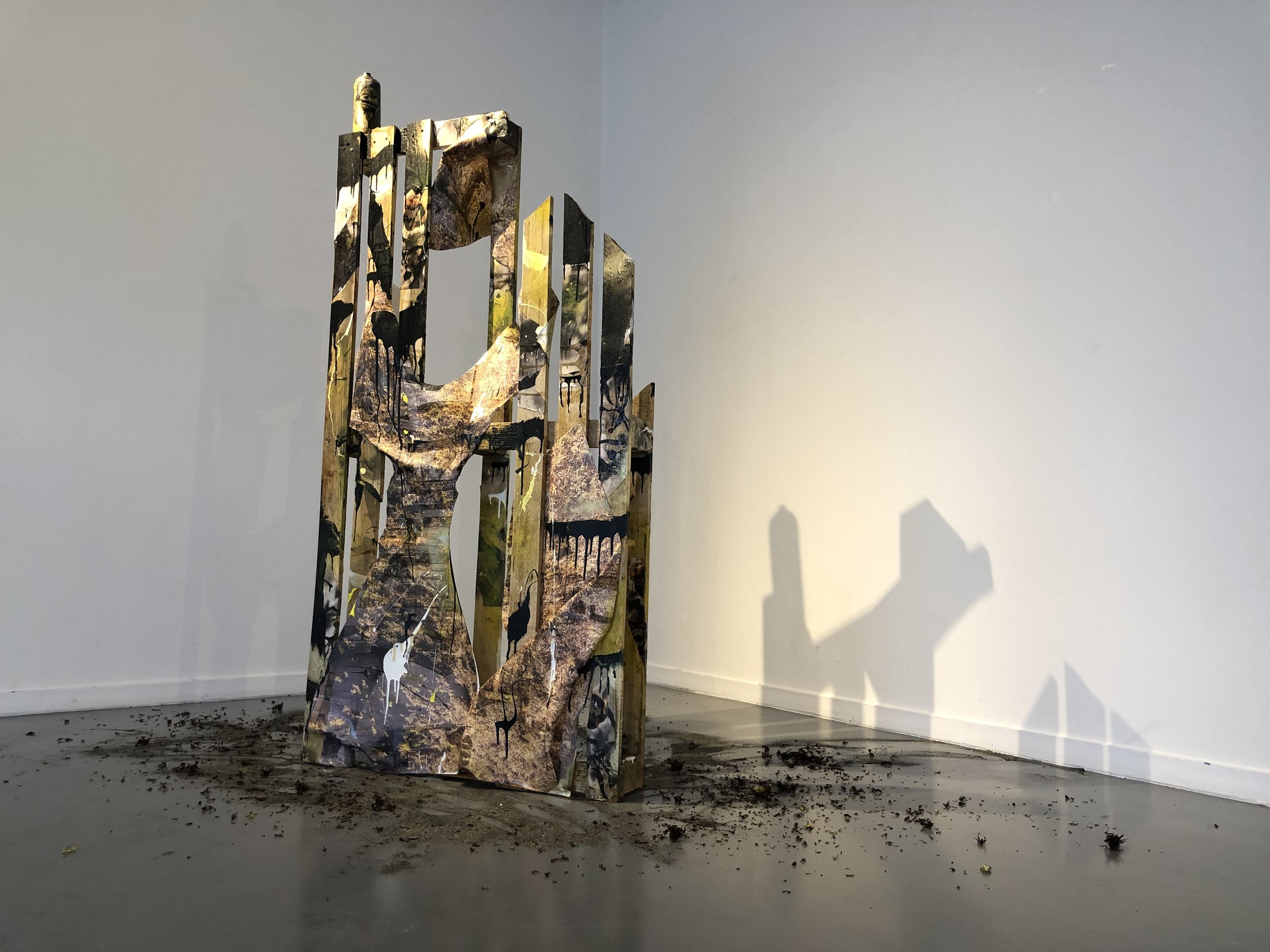Une sculpture faite d'une palette de bois recouverte de photographies imprimées sur toiles. Cette oeuvre de Louisa Marajo représente une palette transportant des sargasses en guise de marchandises du futur.