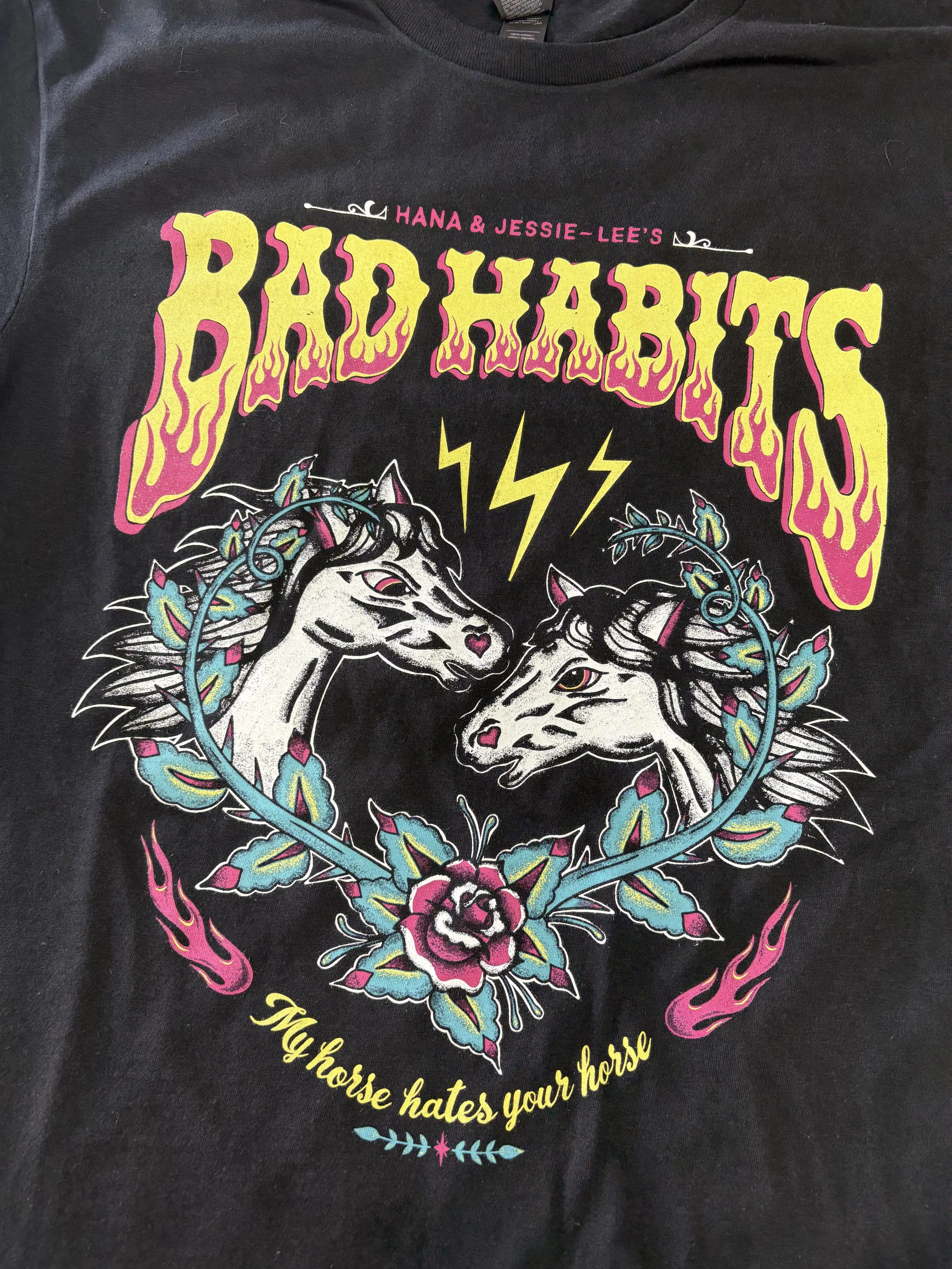Colourful Bad Habits screen print with unicorns and a floral heart on a black T-shirt.