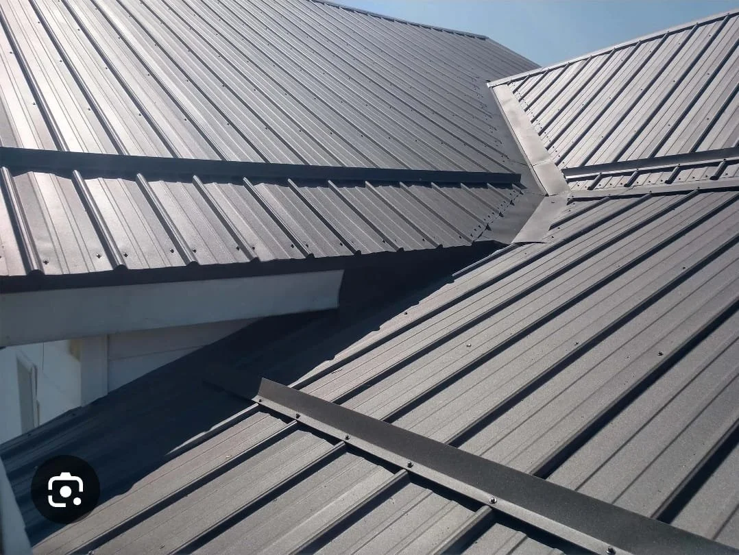 Close-up view of a metal roof with multiple intersecting sections and seams.
