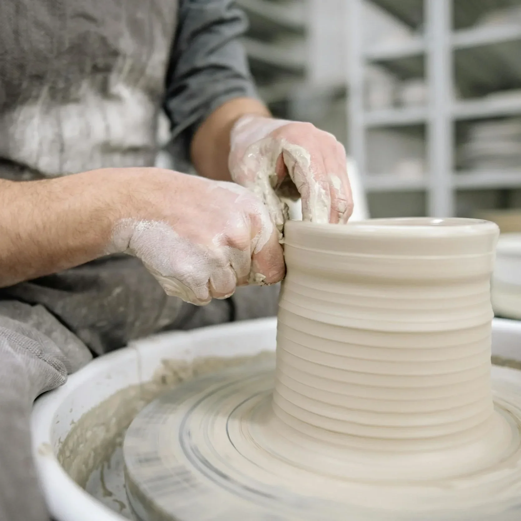 Close-up of a person's hands shaping a piece of pottery on a pottery wheel.