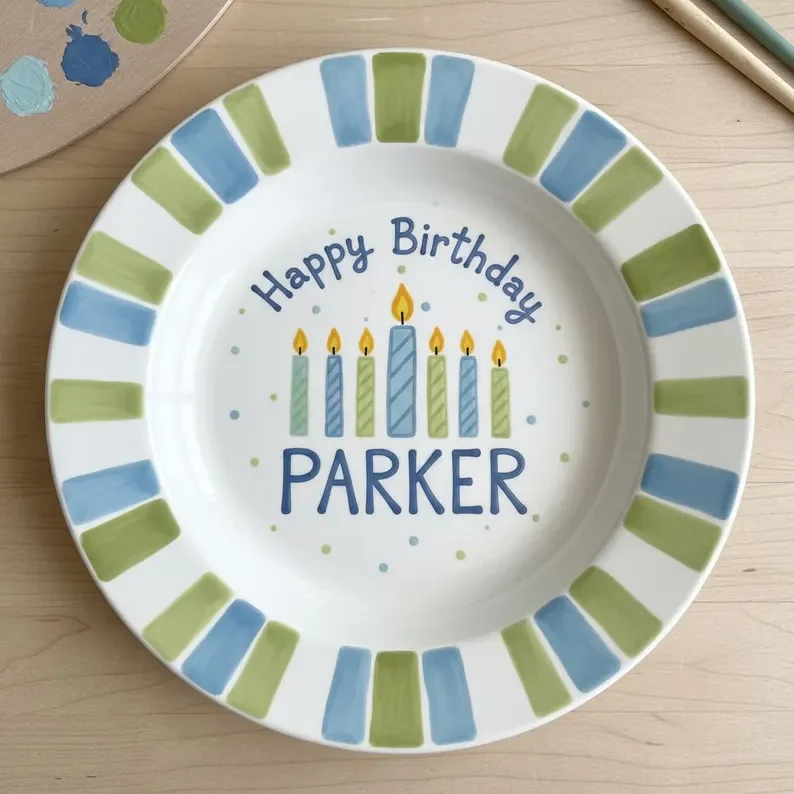 A decorated paper plate with candles drawing and the words "Happy Birthday Parker" in blue, surrounded by blue and green border stripes.