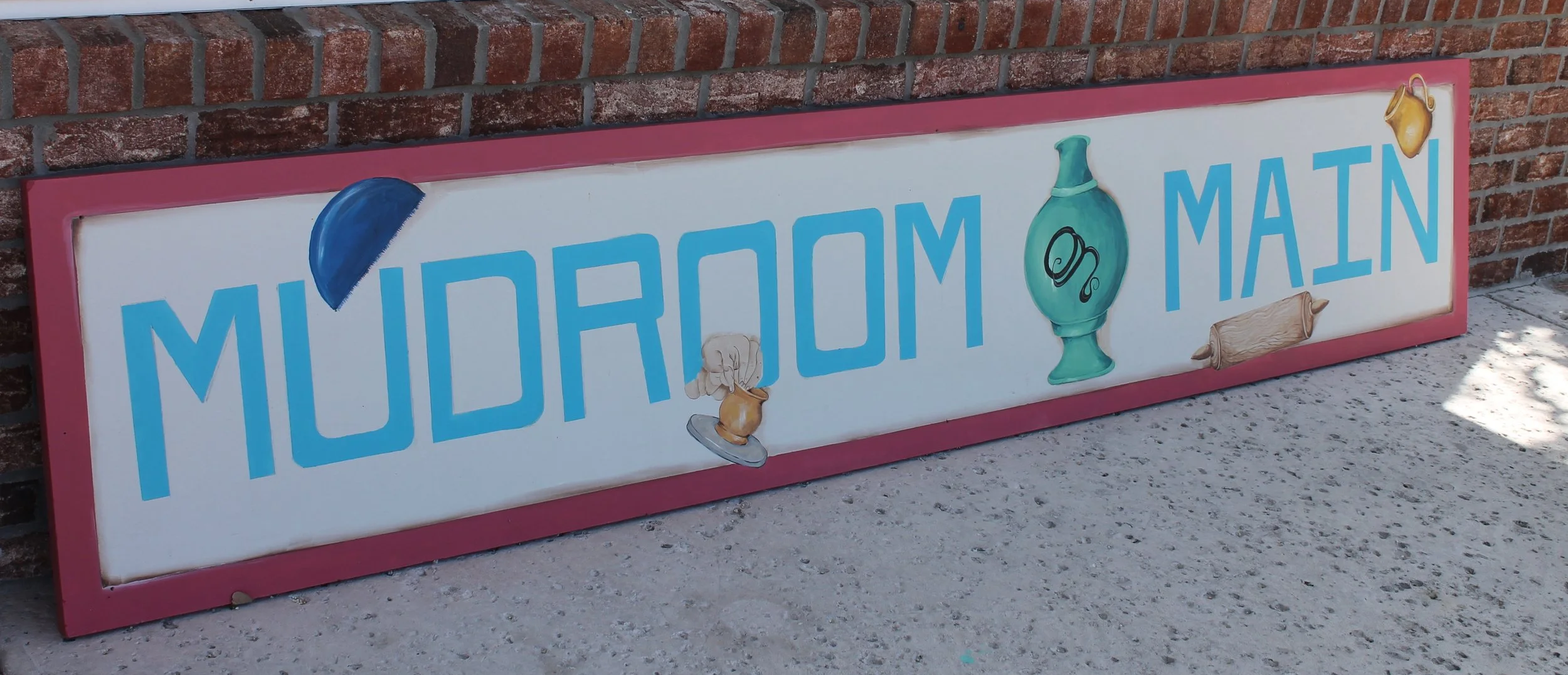 Sign reading 'Midtown Main' with illustrations of a blue hat, a green vase, a wooden rolling pin, and a beige teapot.