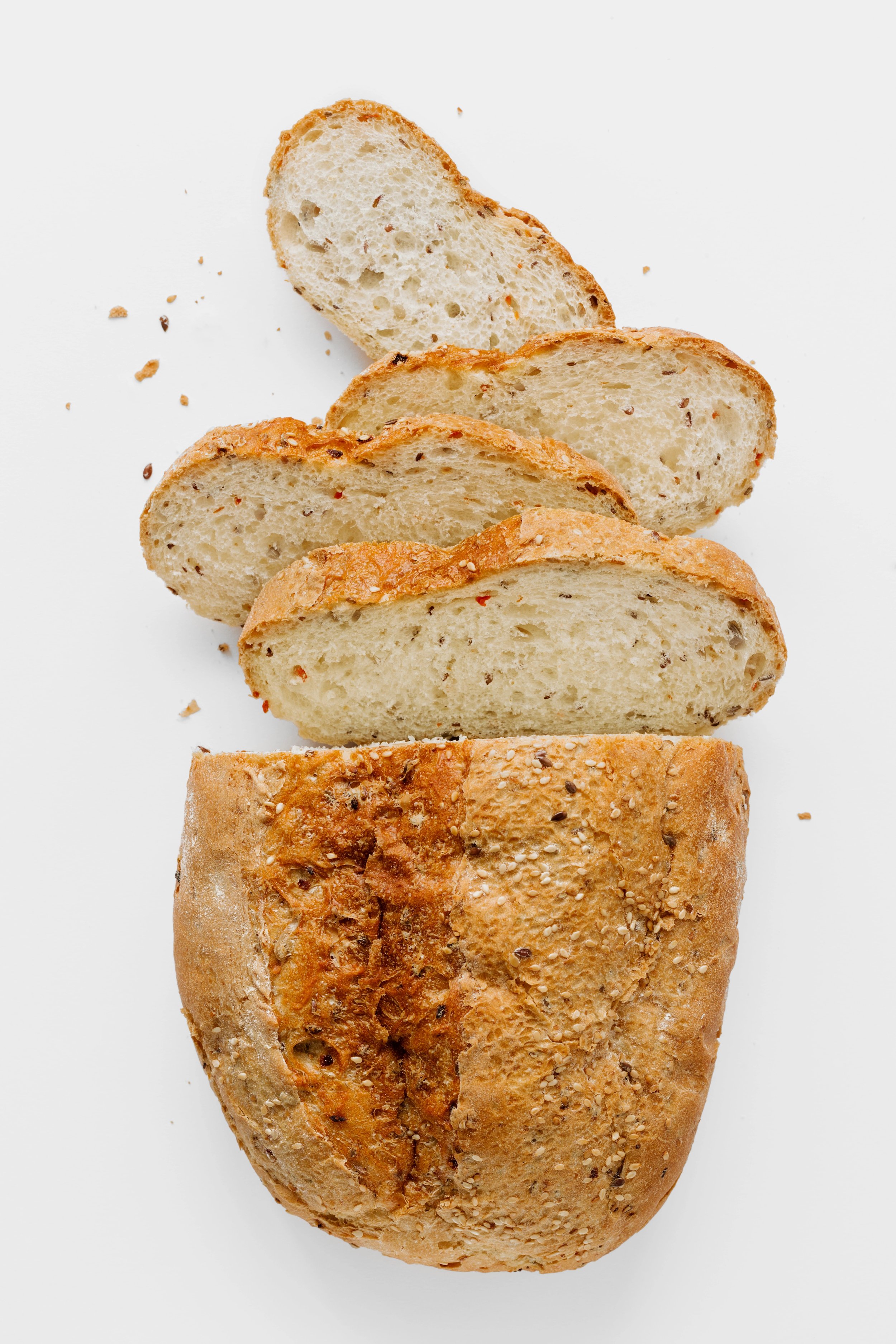 Sliced loaf of multigrain bread on white background