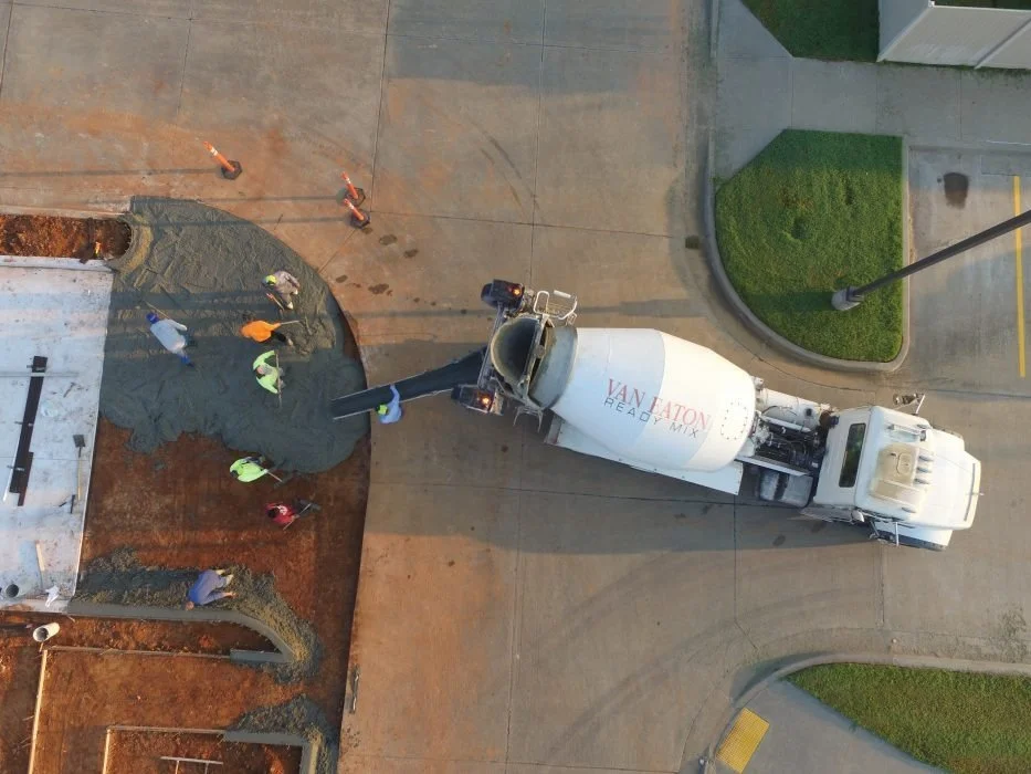 Construction workers pouring concrete from a cement mixer truck at a construction site.