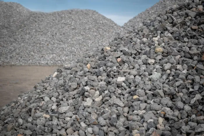 Large piles of gray crushed rock or gravel outdoors under a blue sky