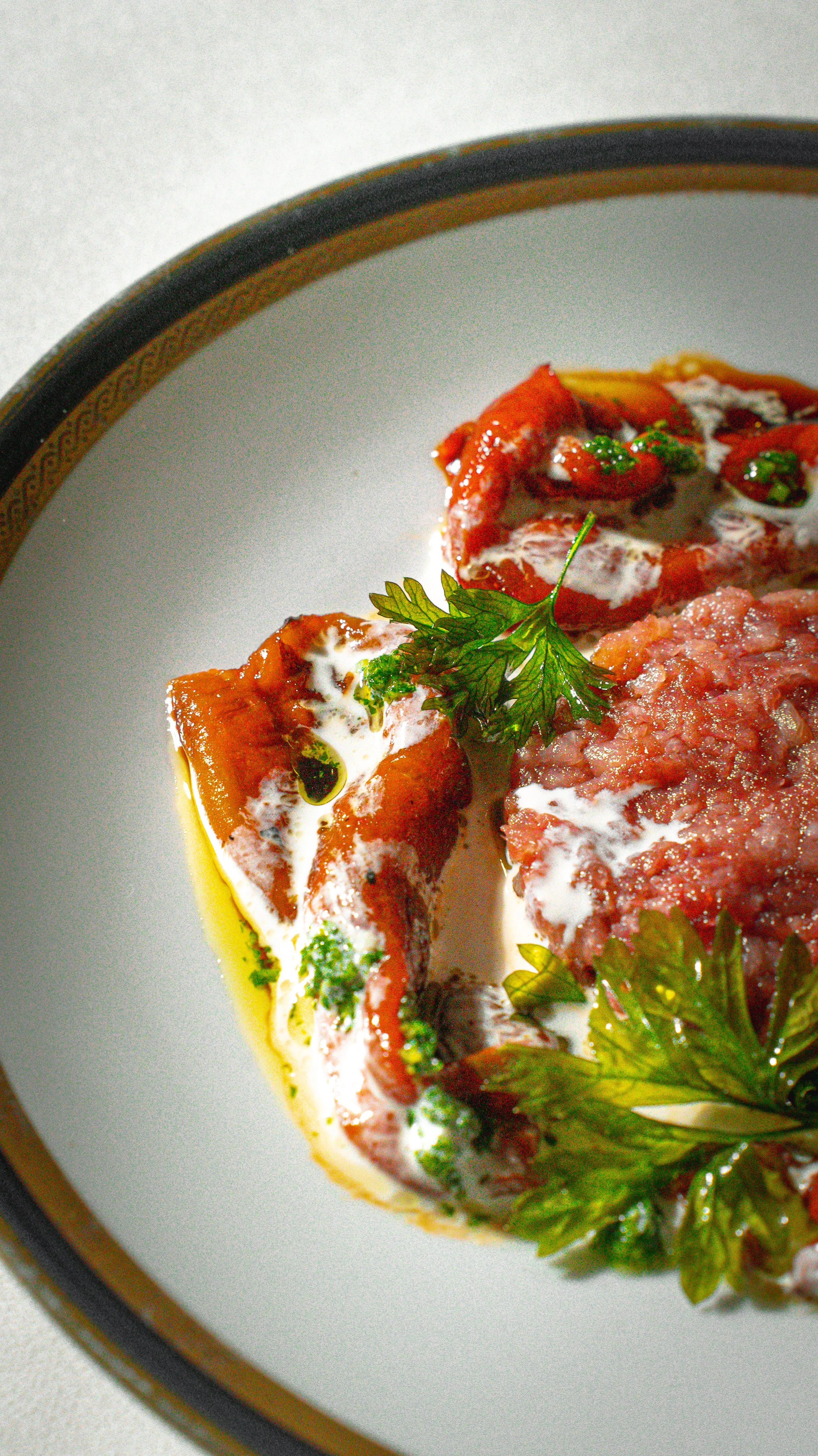 Fetta di formaggio con pomodoro e erbe aromatiche, con olio d'oliva, su piatto bianco