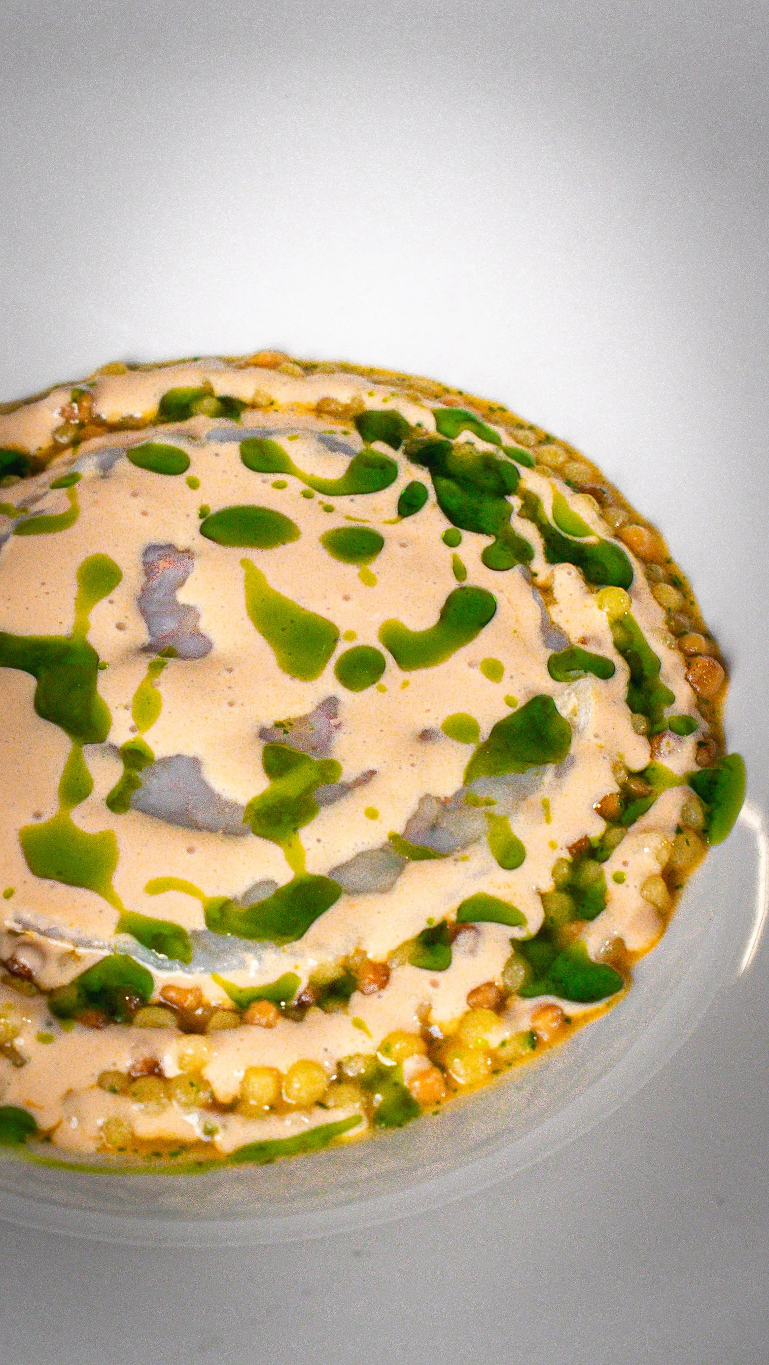 Dolce con crema e granella di mandorle, decorato con gocce di salsa verde.