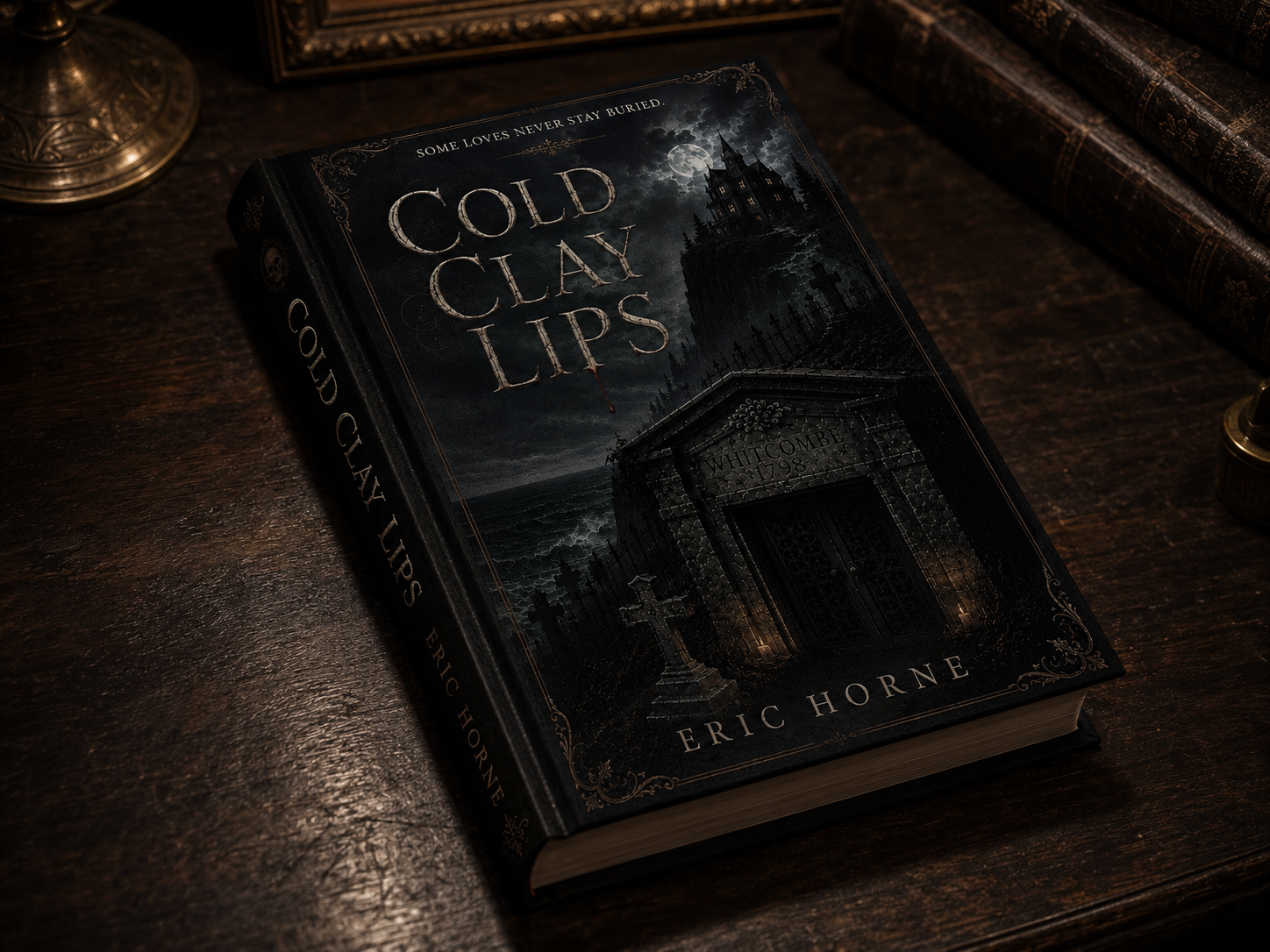 A book titled 'Cold Clay Lips' by Eric Horne on a dark wooden surface, with a gothic-style house and graveyard depicted on the cover under a full moon and cloudy sky.