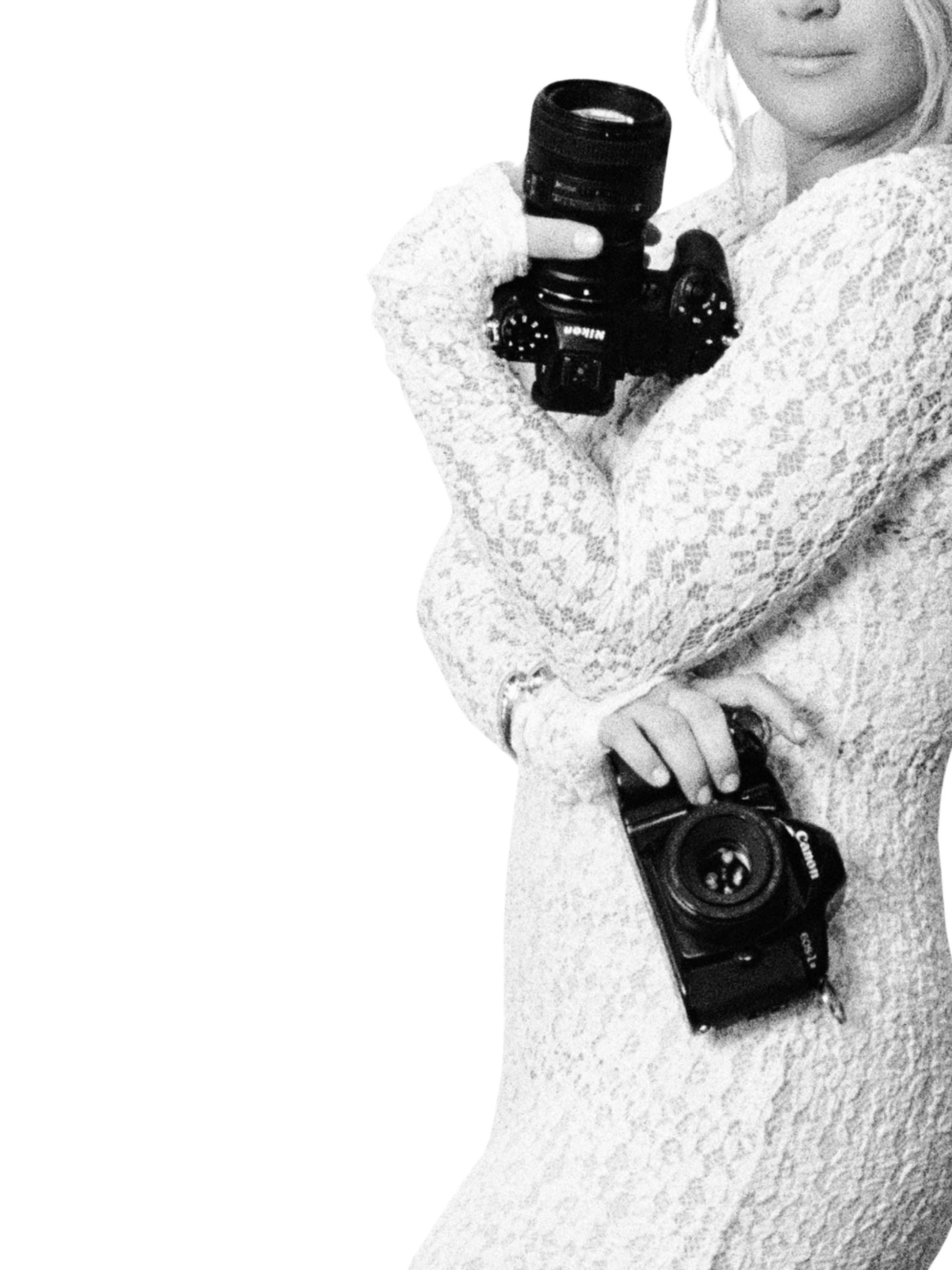 A person wearing a white lace top holding a black camera with a lens in their right hand.