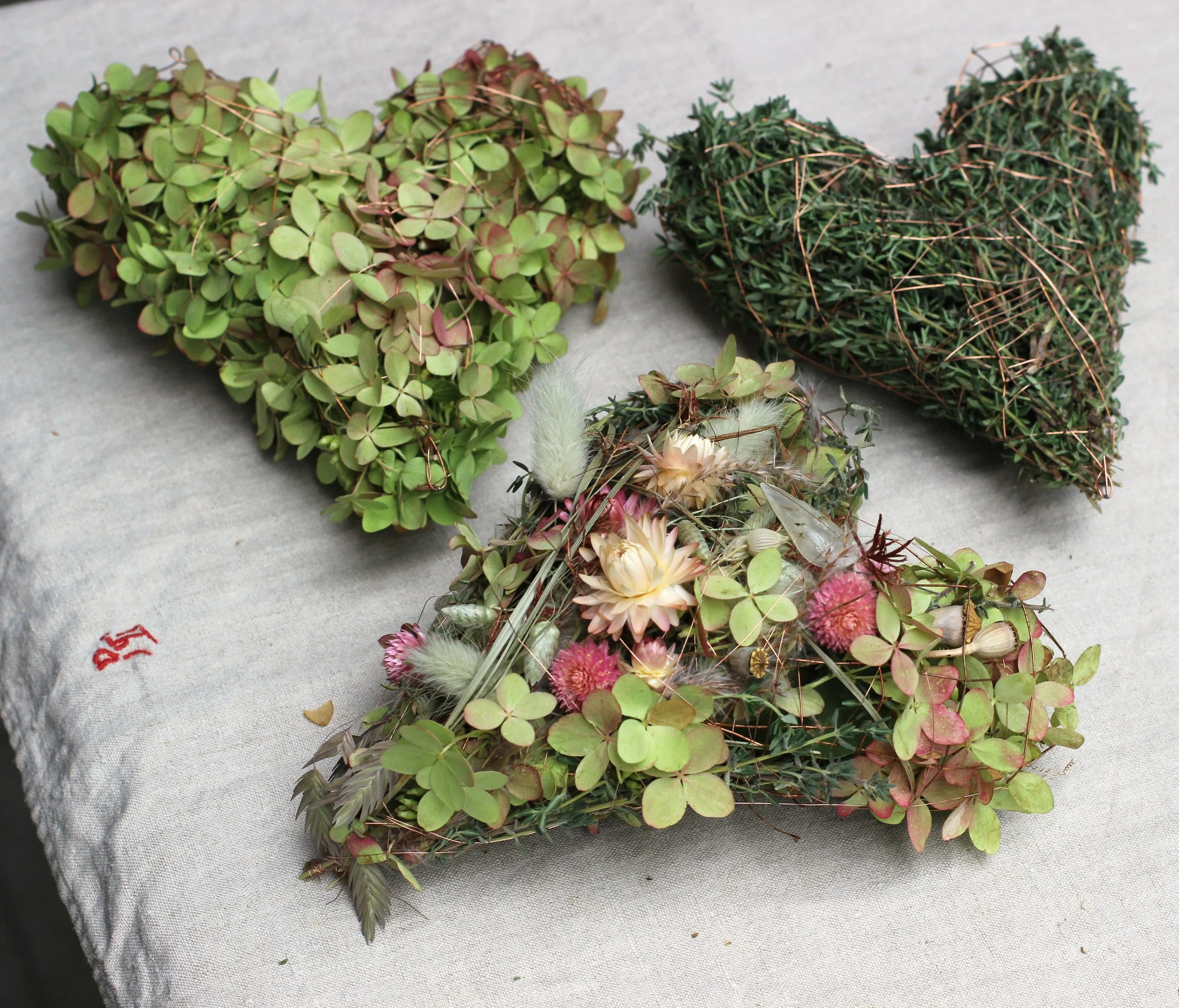 verschiedene Blumenherzen aus Hortensien, Kräutern und verschiedenen Trockenblumen
