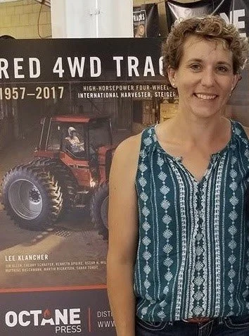 Sarah standing in front of a display board about a red 4WD tractor.