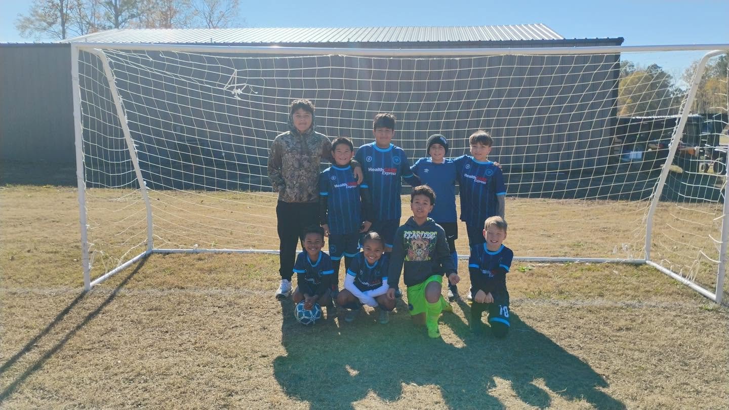Youth soccer team in front of goal on field, group photo