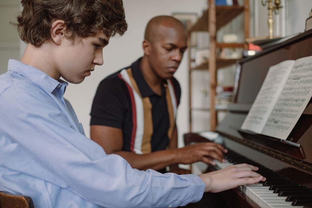 Teacher and student sitting at the piano with right hands playing together