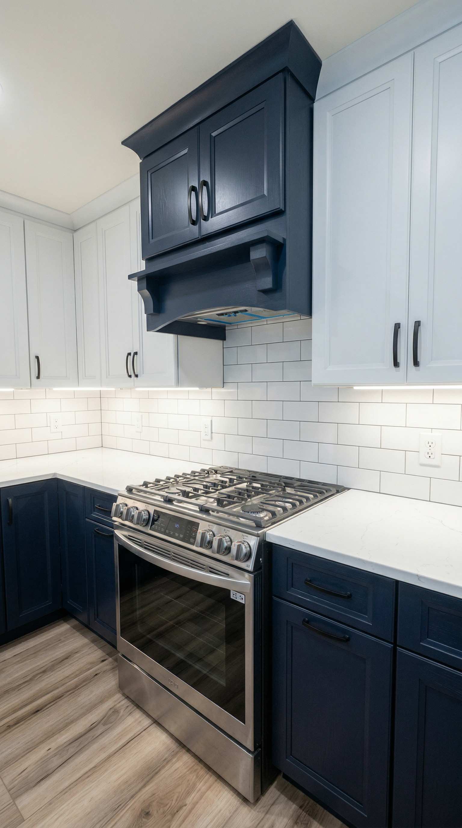 Modern kitchen with navy blue cabinets, white backsplash tiles, a stainless steel gas oven, and white countertops with wood flooring.