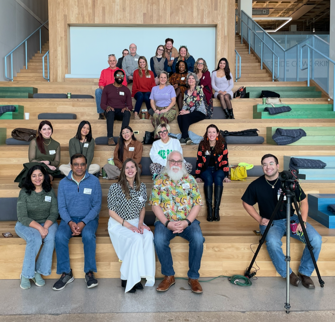Group of diverse people posing on wooden tiered seating area inside a modern building.