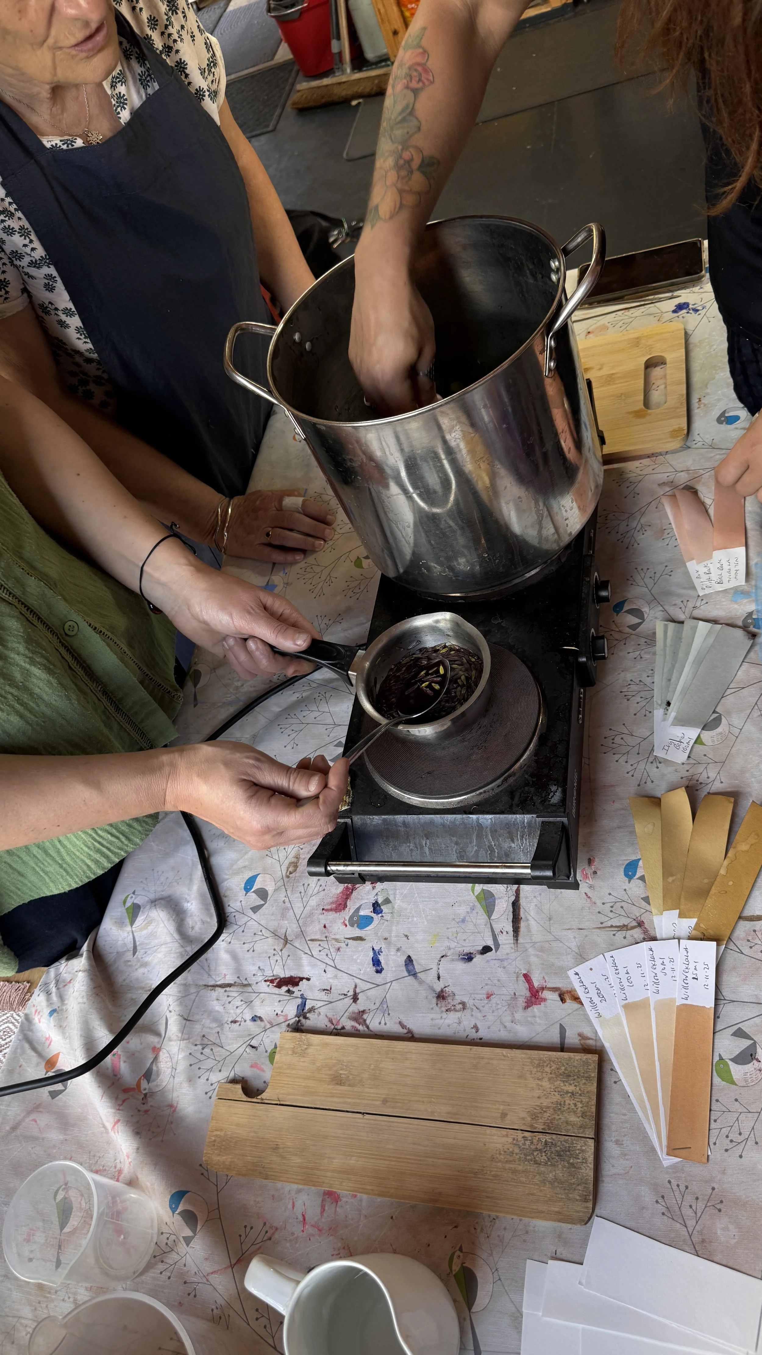 People are participating in a chocolate tasting or comparison event. They are heating and sampling chocolates, with small tasting spoons and samples on display.