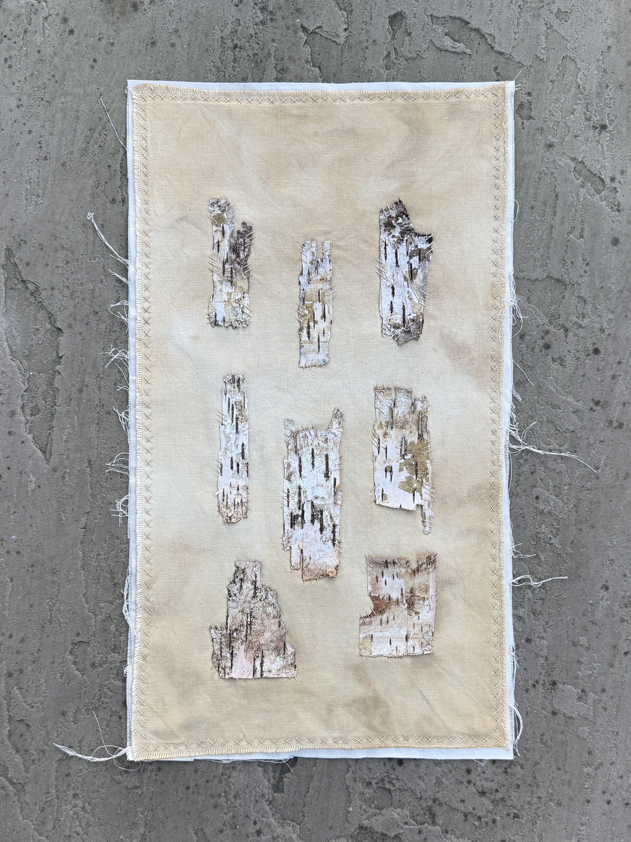 Pieces of birch bark hand stitched onto natural dyed cloth symbolising repairing connection with nature