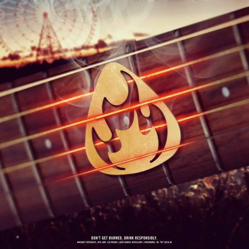 A wooden guitar fretboard with a fire-themed whiskey logo and a sunset background, with fiery light streaks across the image.