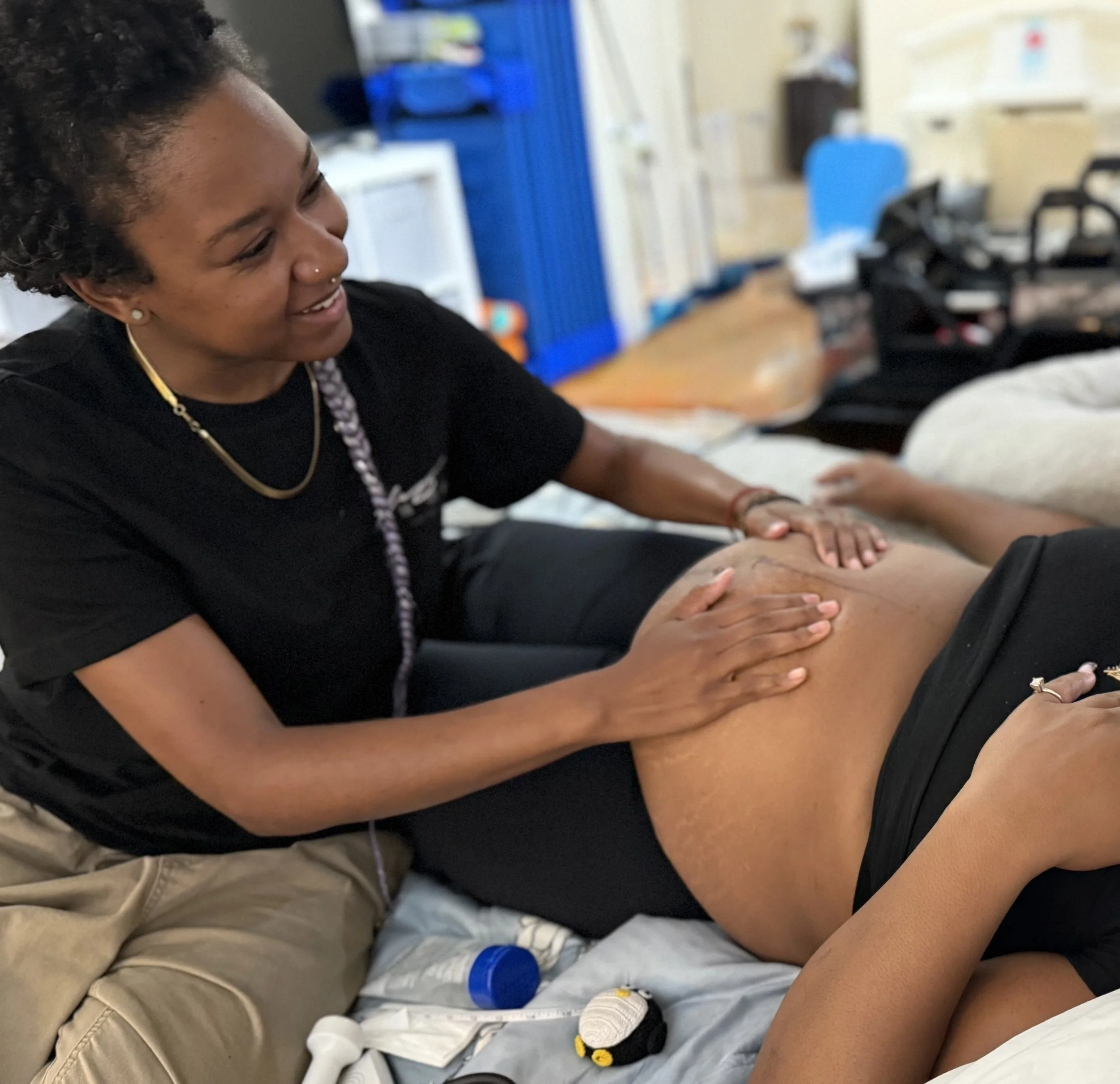 A woman with curly hair receiving a massage on her back in a treatment room.