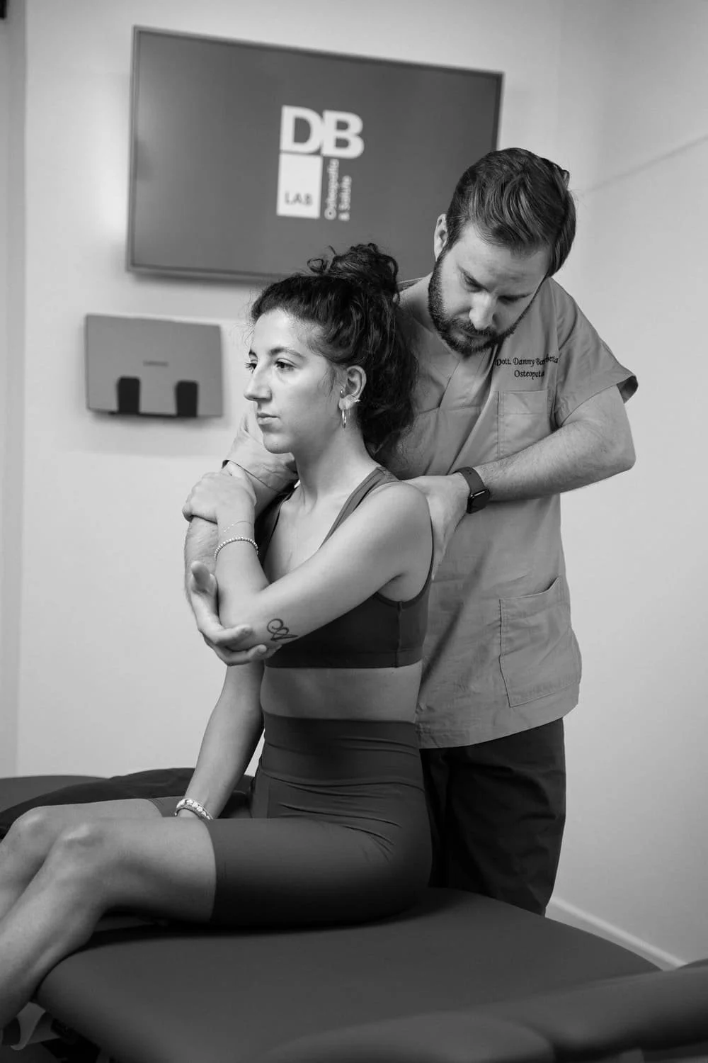 A male chiropractor adjusting a female patient's neck in a medical office.