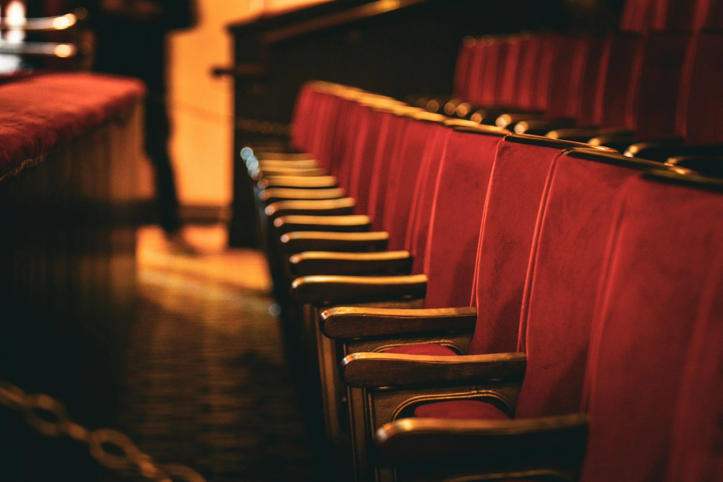 Rijen rode theaterstoelen in een donkere zaal.