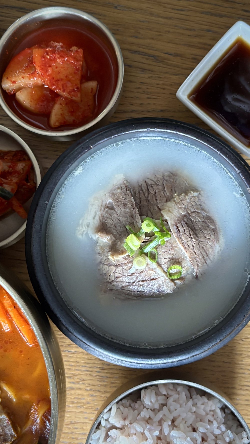 Seolleongtang with sliced beef and spring onion in milky beef bone broth, served with rice and radish kimchi at Misty Pot.