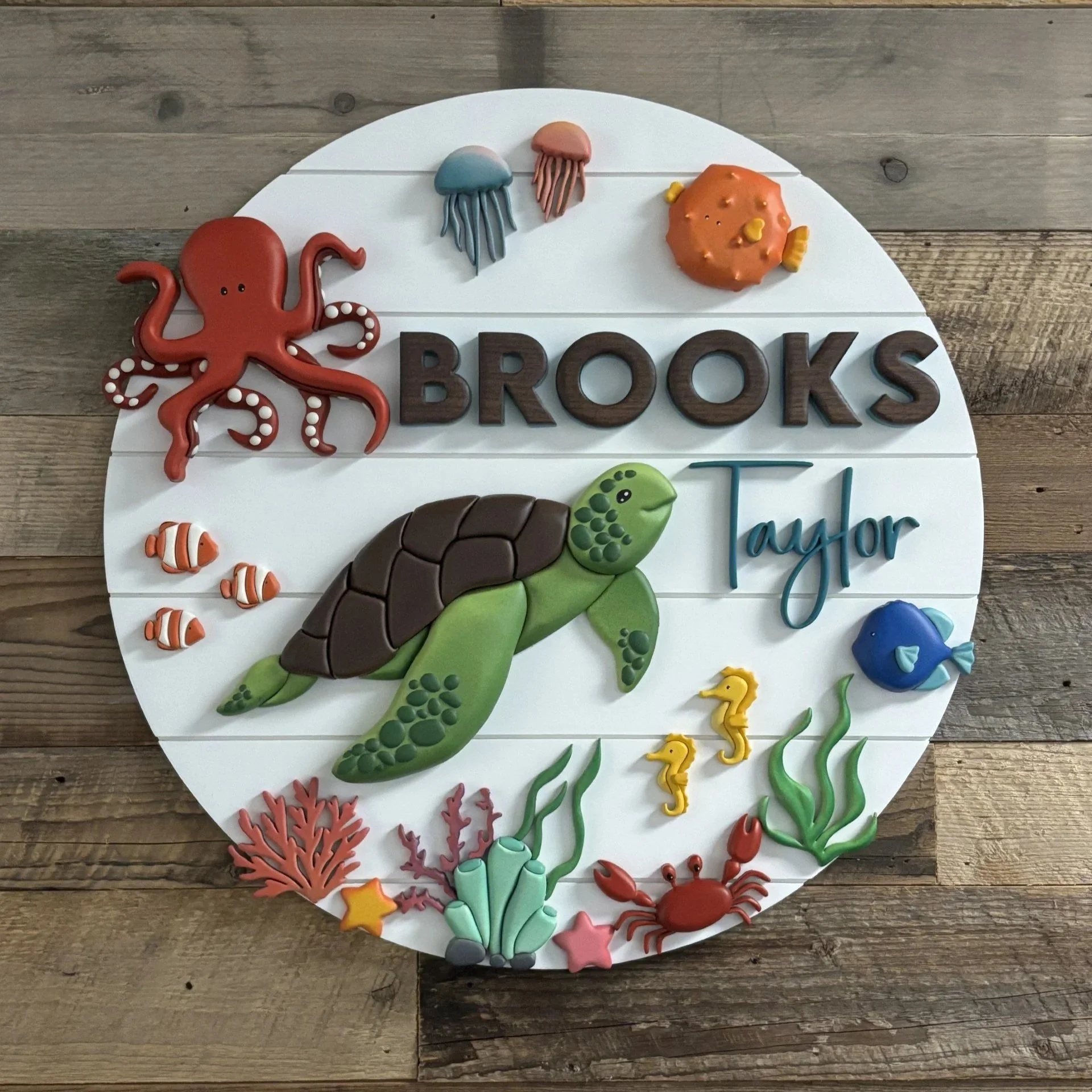 Decorative cake with ocean and seafood theme, includes a red octopus, fish, seaweed, starfish, and crab, with the words 'BROOKS Kindergarten' in chocolate letters.