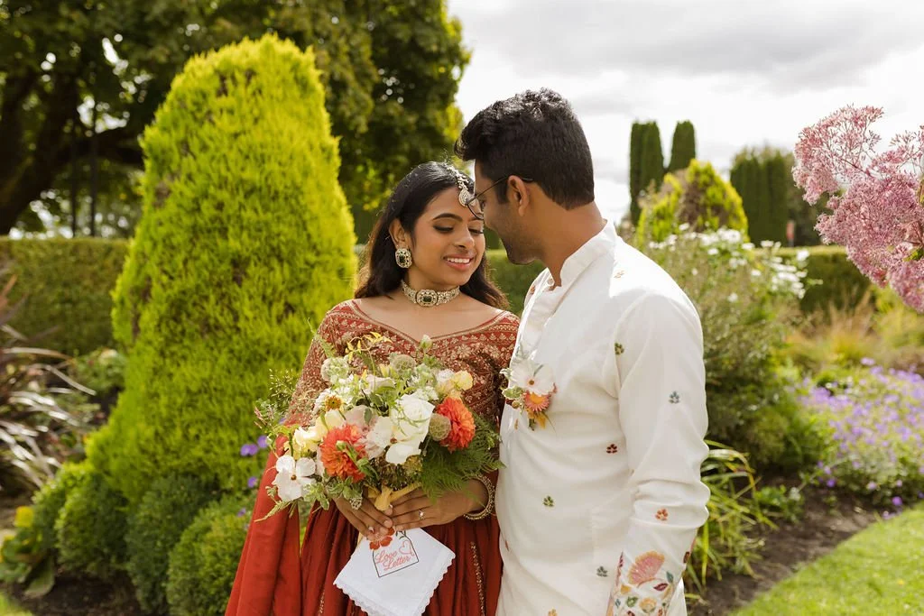 Indian couple holding a colorful bridal bouquet at a Seattle Wedding Hall by Love Letter Floral and Events