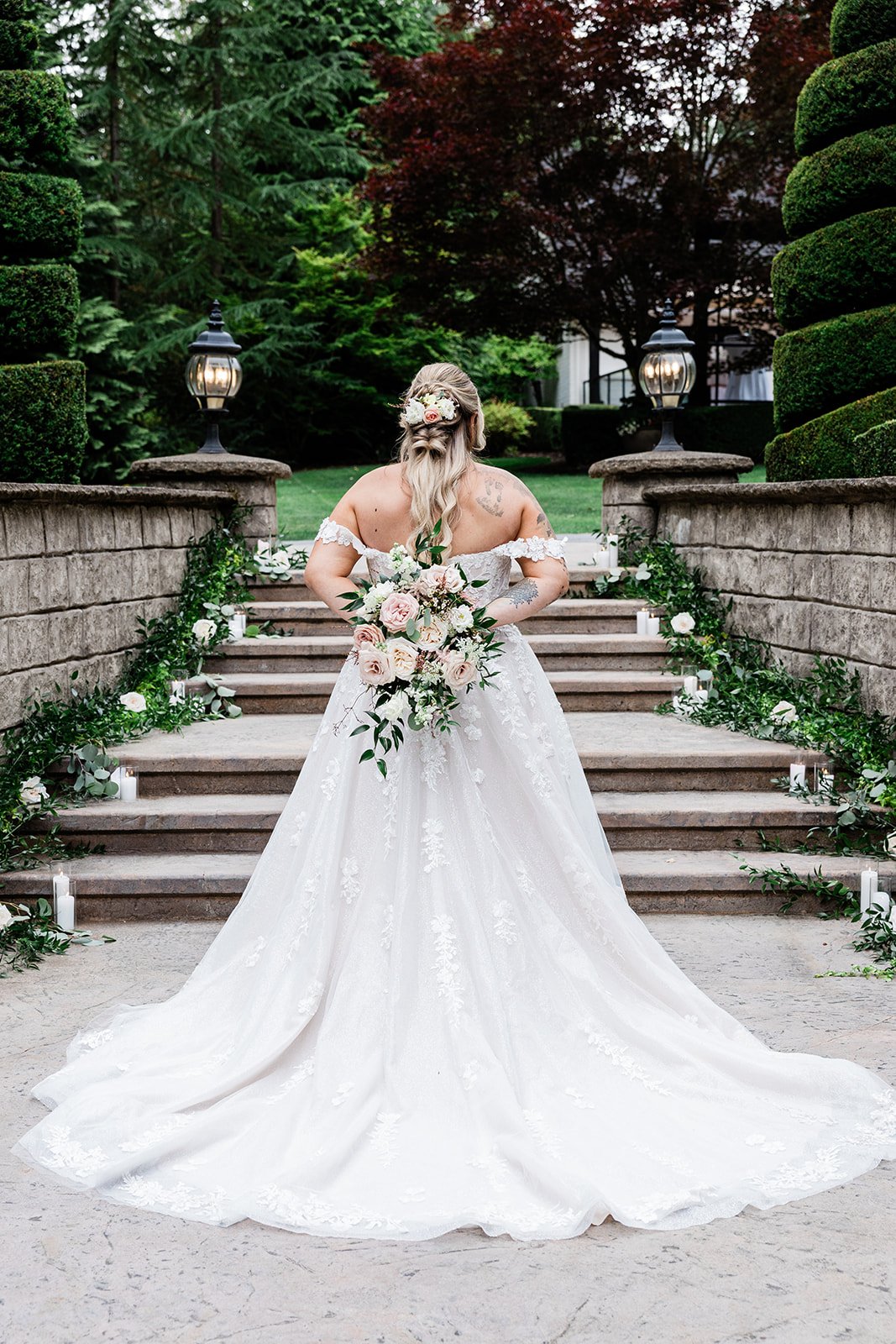 bride holding Cascading blush and white bridal bouquet  around her back by Love Letter Floral and Event