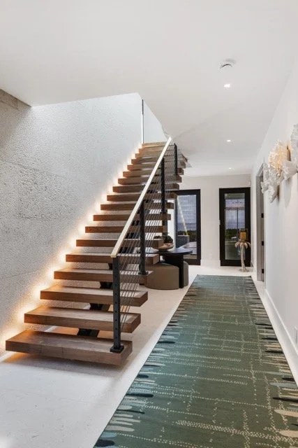 Linear lighting running the length of a floating oak staircase in an oceanfront entry