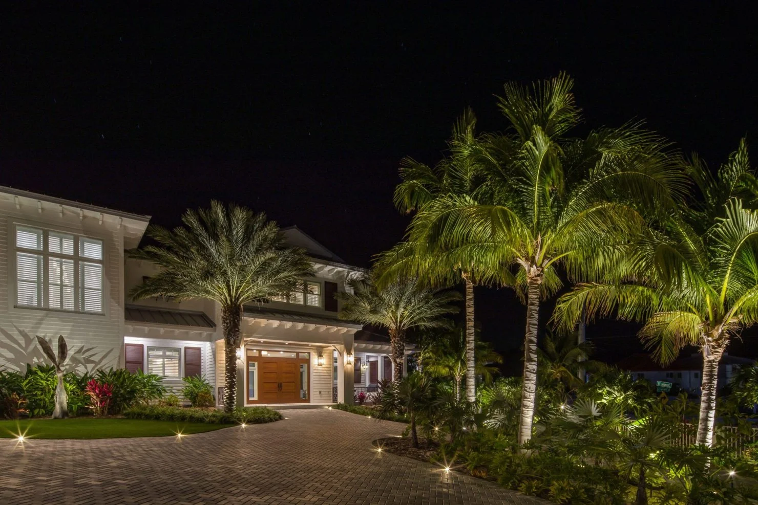 Night view of a house with palm trees and landscape lighting
