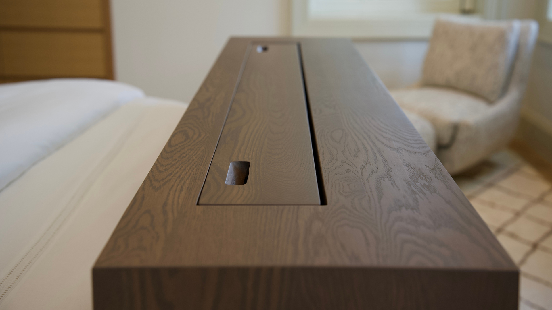 Oak footboard cabinet with a concealed television lift closed flush into the millwork