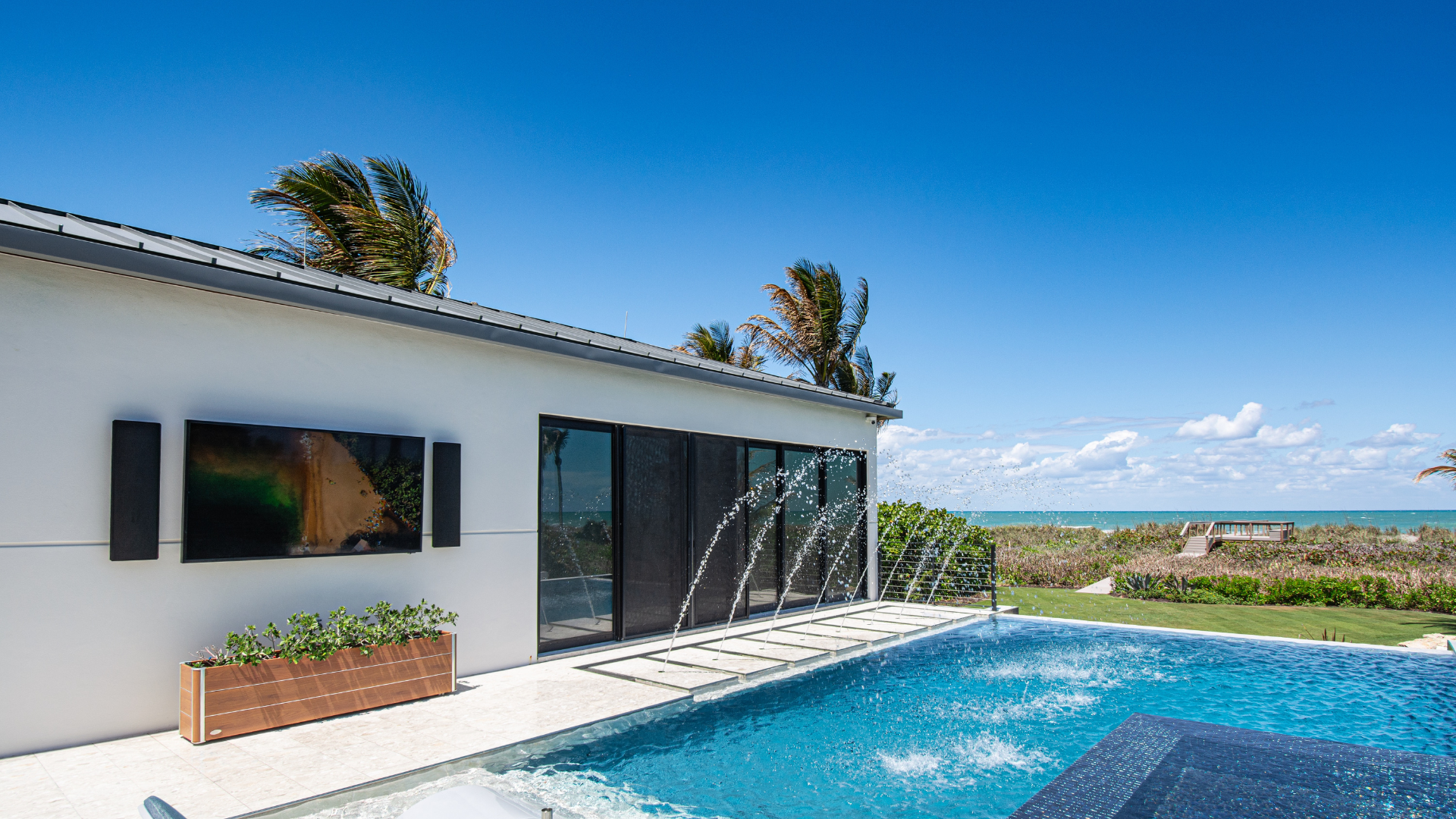 Outdoor-rated television and speakers on the pool deck, facing the water