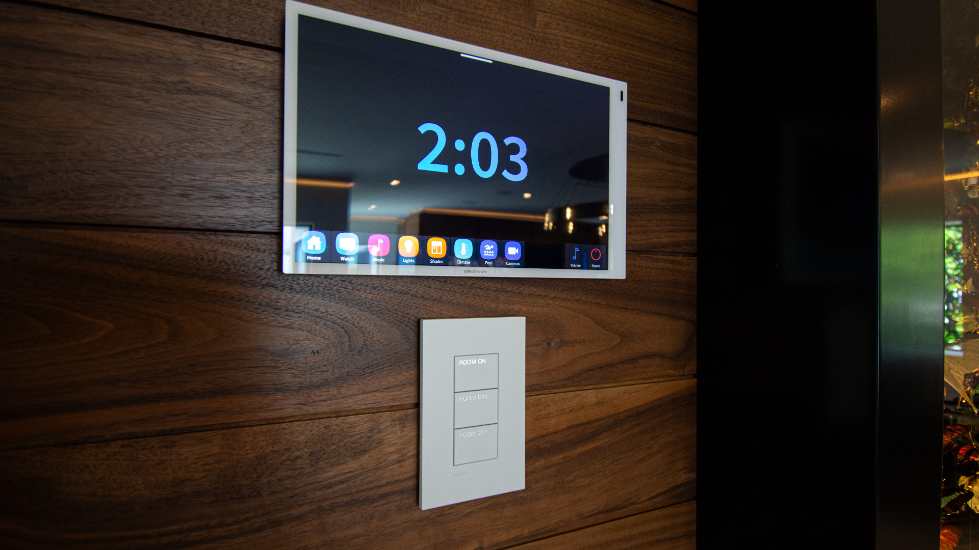 Control touchscreen and lighting keypad set into a walnut wall, aligned to the millwork