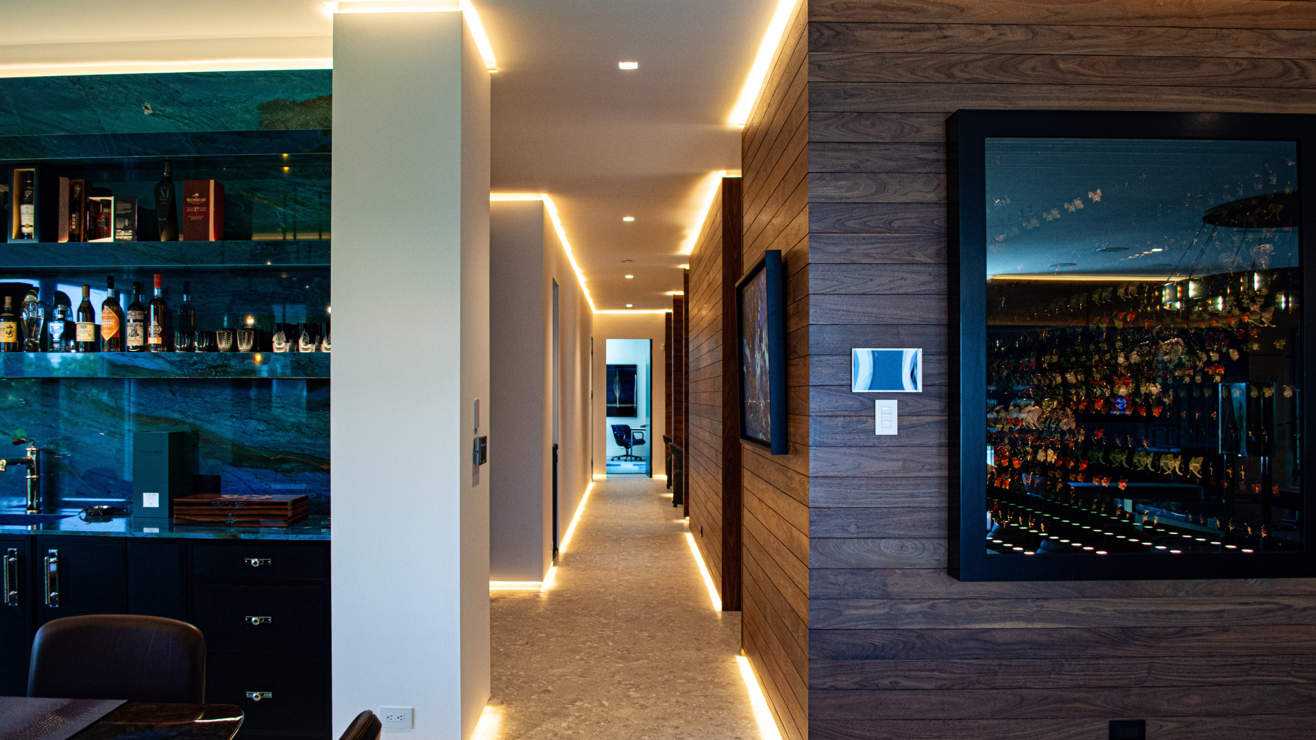 Cove lighting along a walnut hallway, with a backlit bar and keypad control at the wall