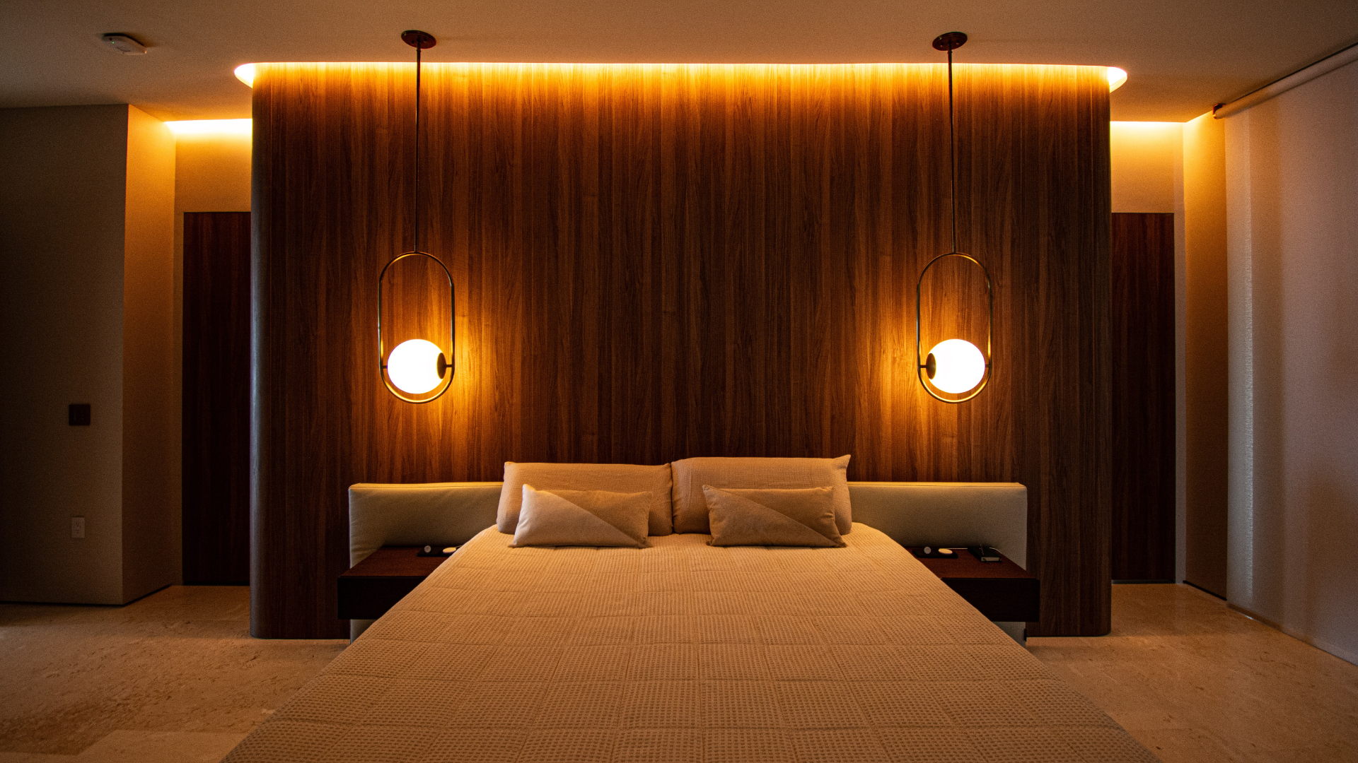 Primary bedroom in the evening, the same fixtures warmed to a golden tone