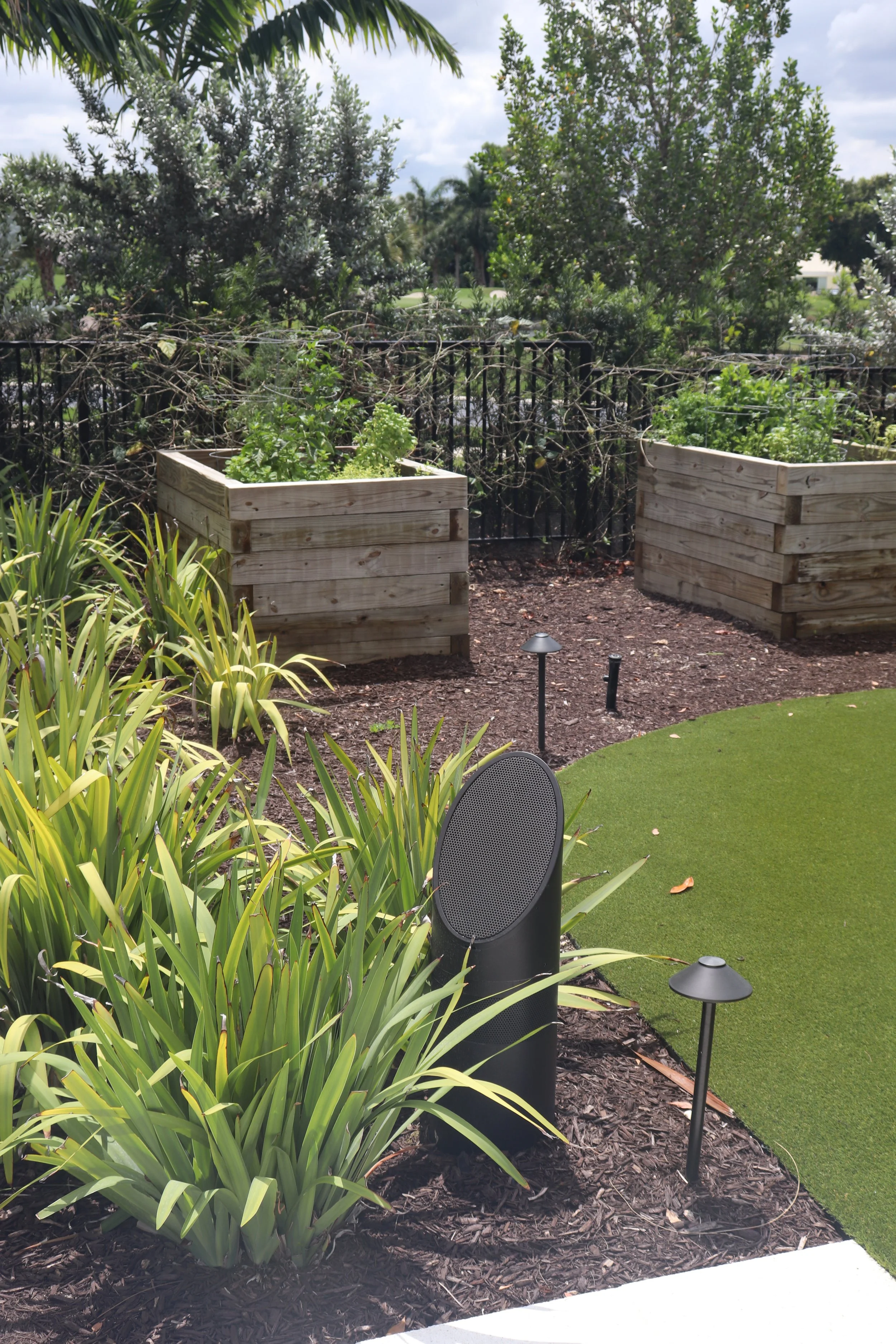 Coastal Source landscape speaker and path lighting set into the planting beside the putting green