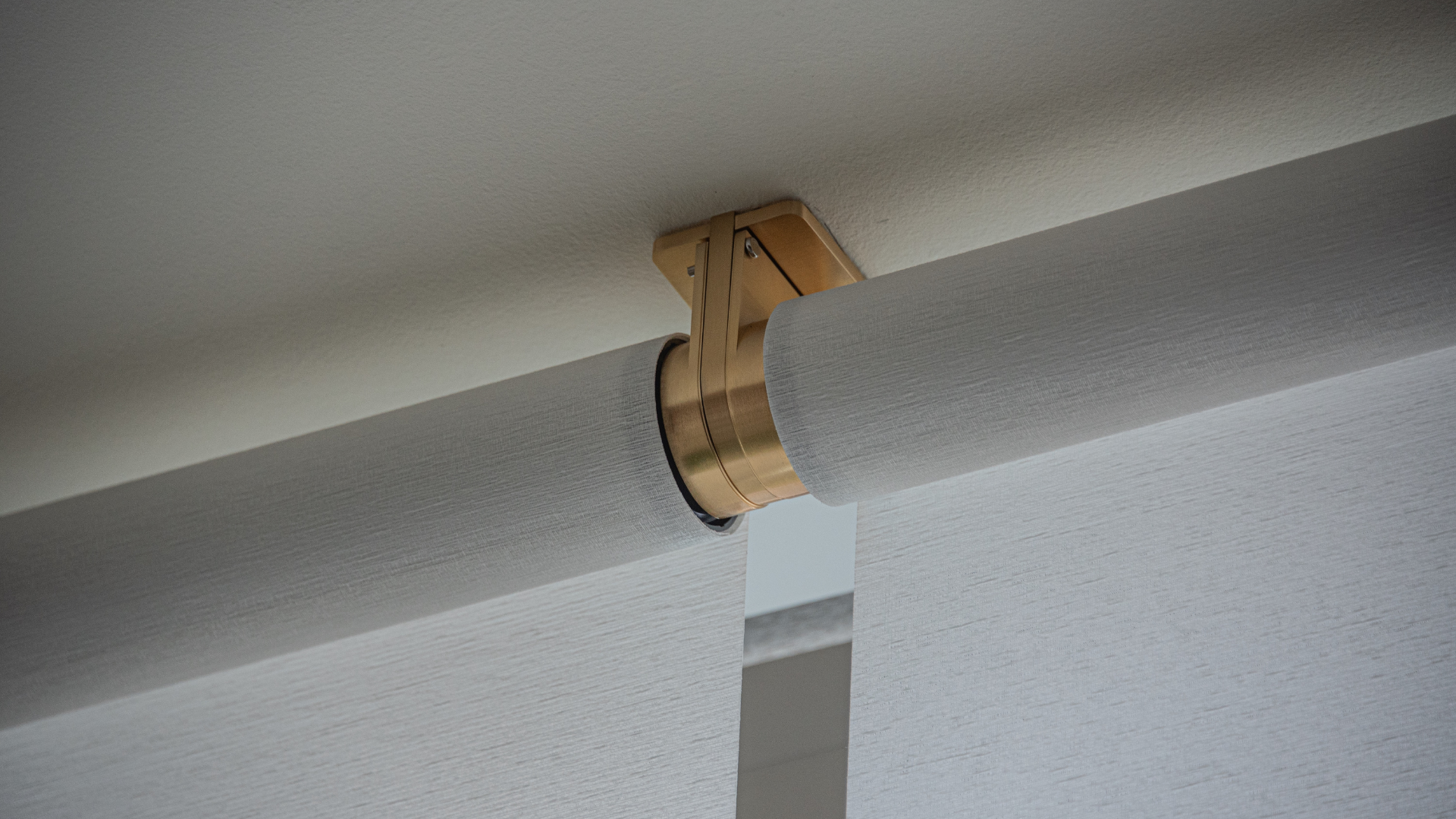 Motorized shade bracket finished in brass, coordinated with the room rather than added to it