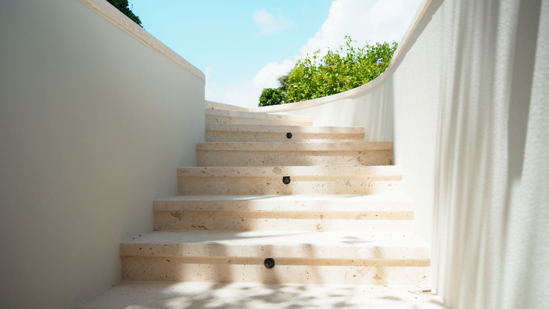 Step lights recessed into limestone stairs, marking the treads without a visible fixture