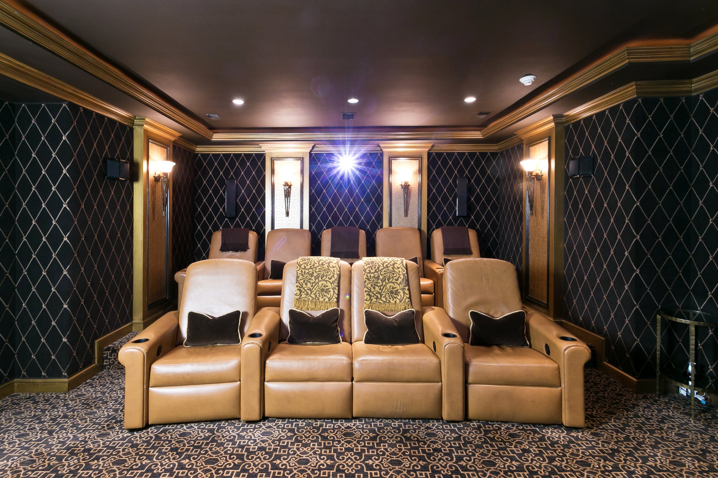 Home theater with two rows of tiered leather seating, wall sconces, and a star ceiling