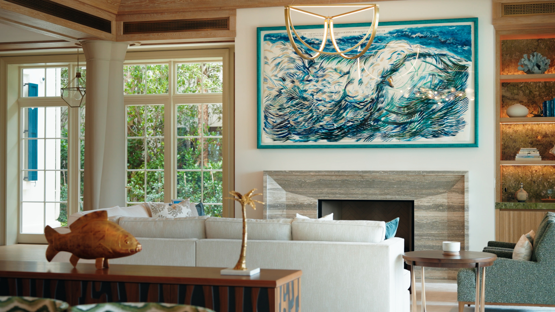 Living room with lit display niches and concealed ceiling speakers above a travertine fireplace