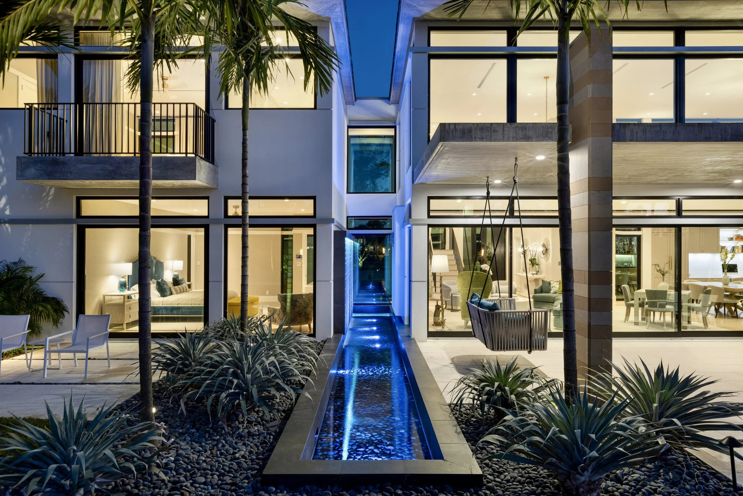 Front elevation and entry at dusk, with exterior lighting on the facade and drive
