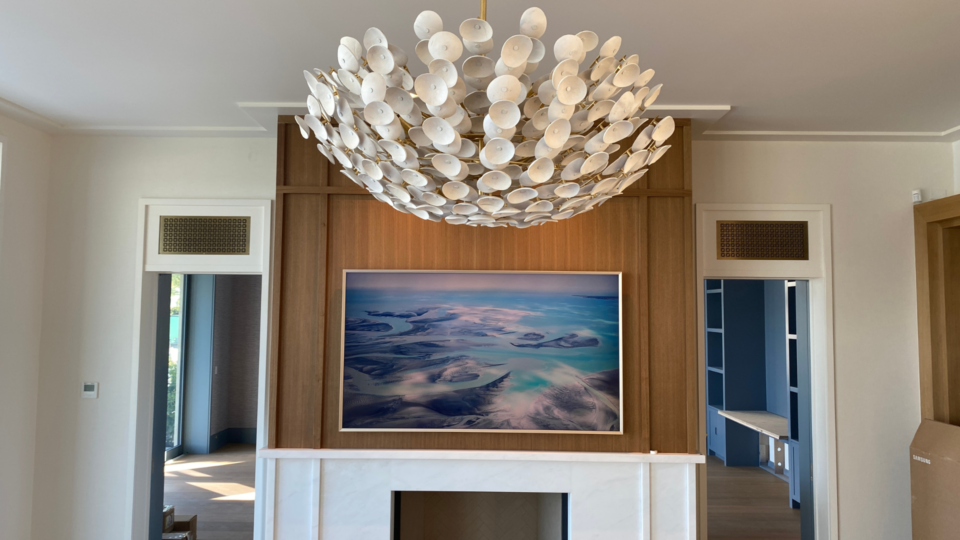 Framed television integrated into oak millwork above the fireplace, reading as art until it's on
