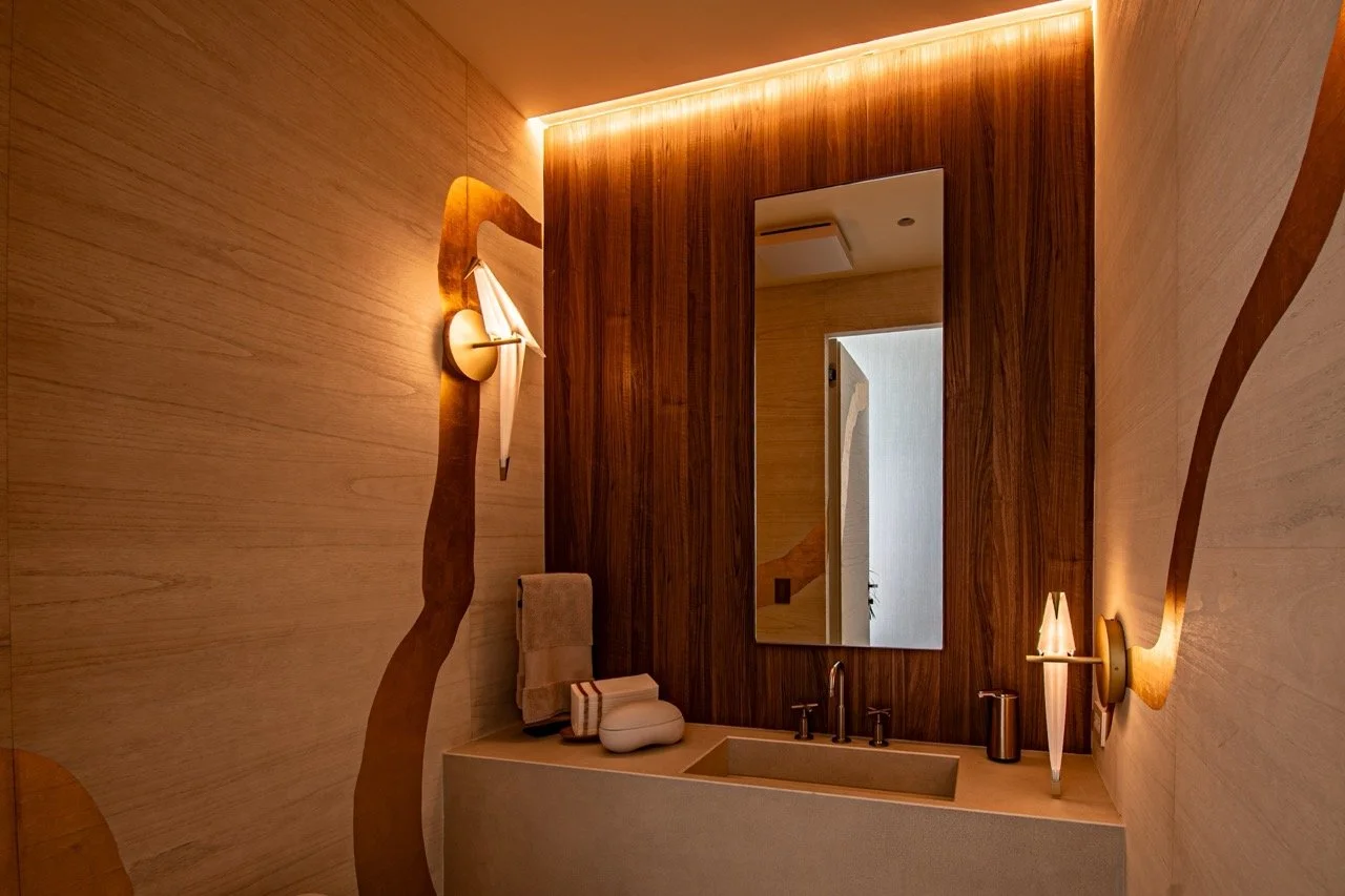 Powder room with warm cove lighting and sculptural sconces