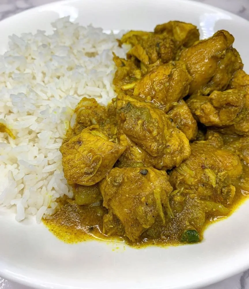 White rice and yellow chicken curry on a white plate.