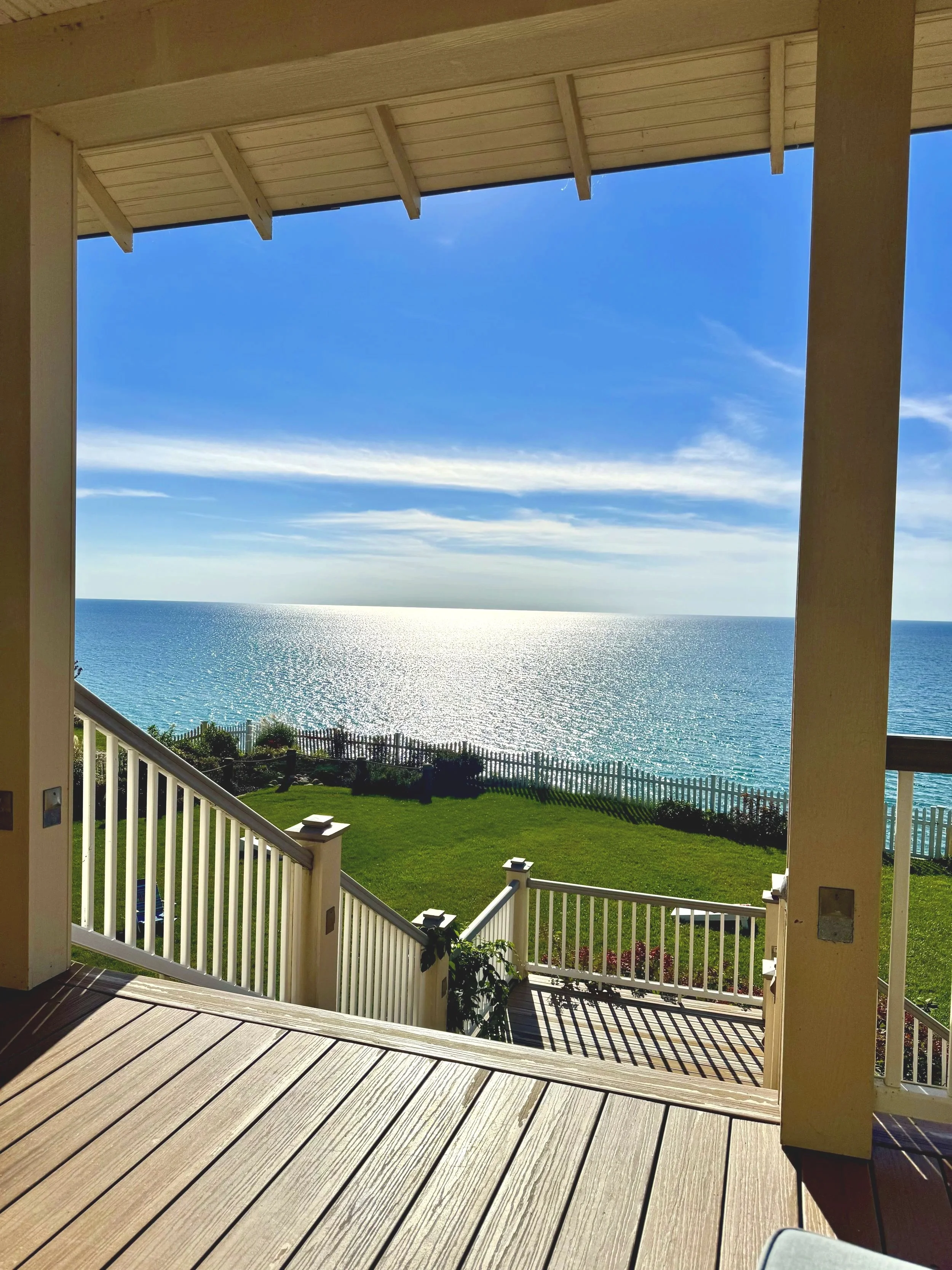 View from the balcony overlooking Lake Michigan, with a white picket fence and a fire pit area.